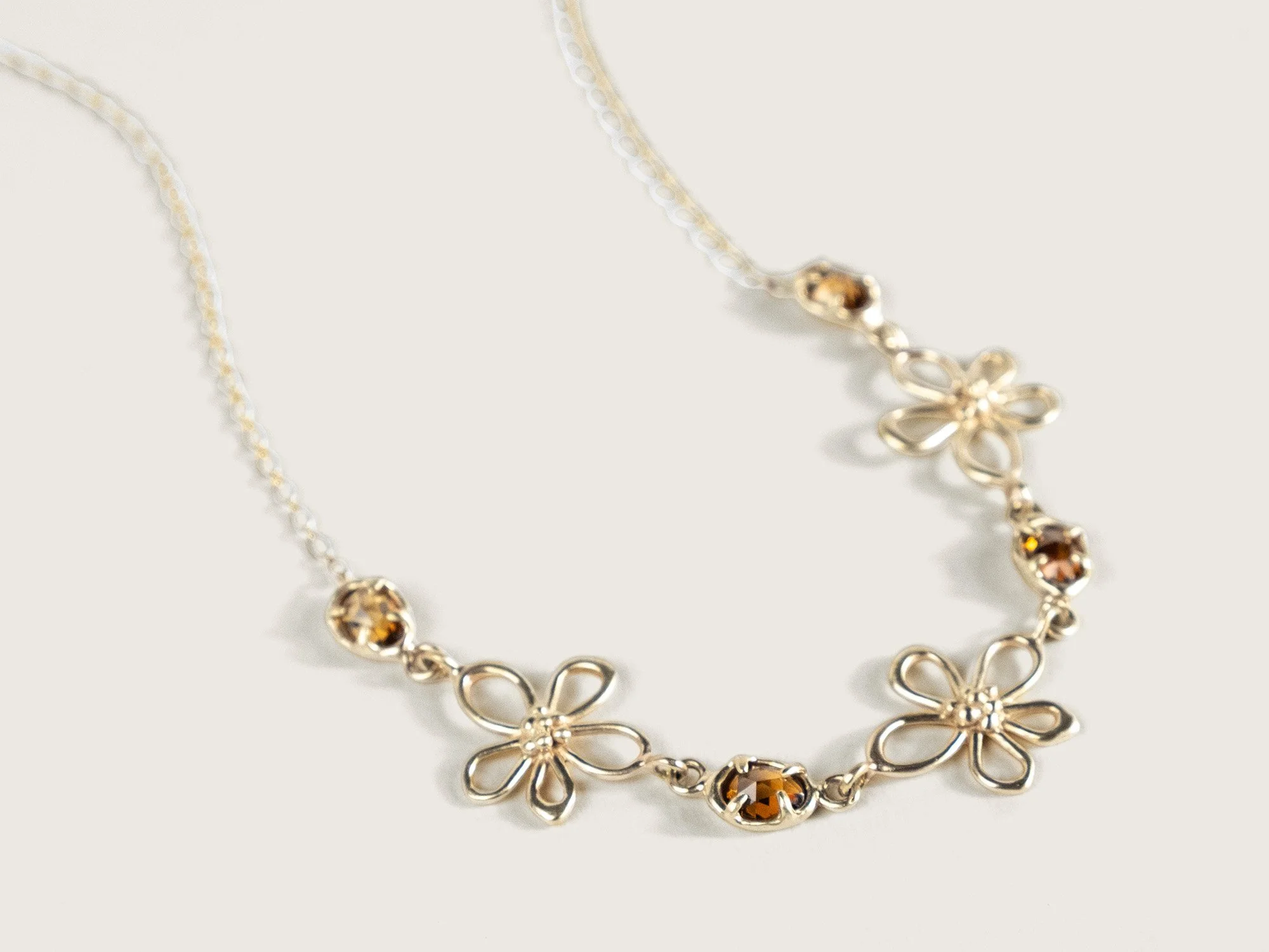 Gold necklace with alternating gold flowers and zircon stones at the front