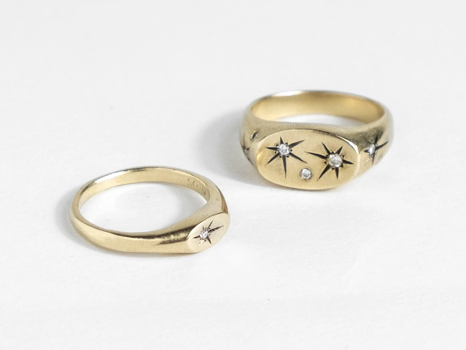 Pair of thin and wide gold signet rings with star-set diamonds on each