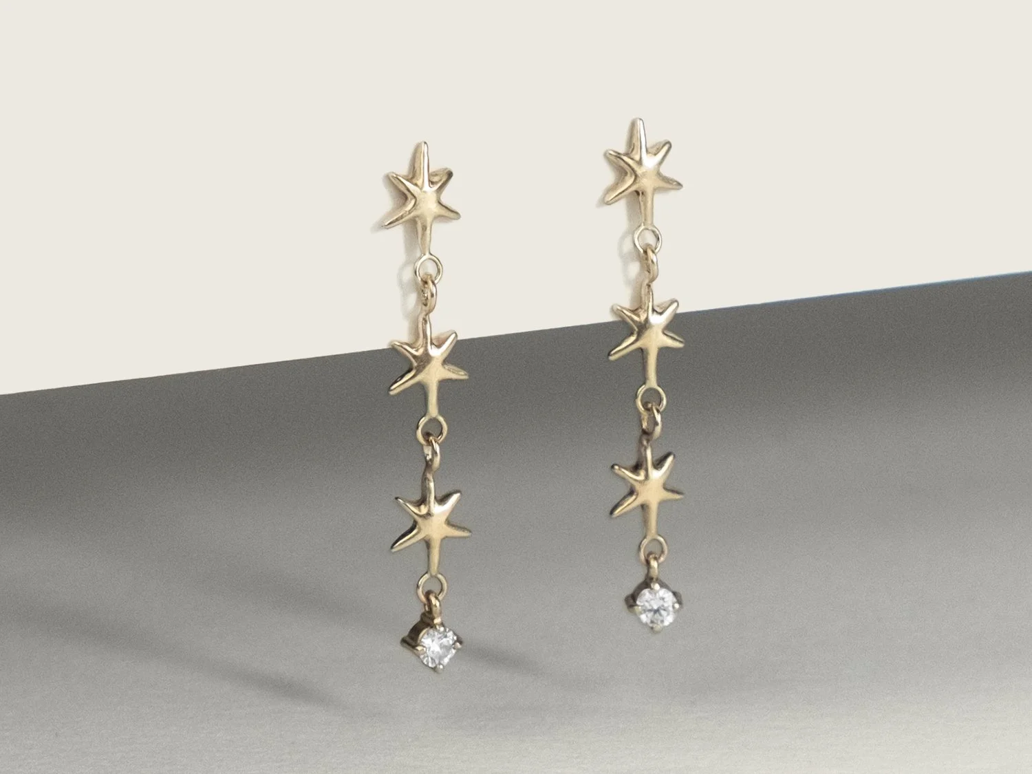 Long gold earrings made of up 3 linked stars and a hanging single diamond
