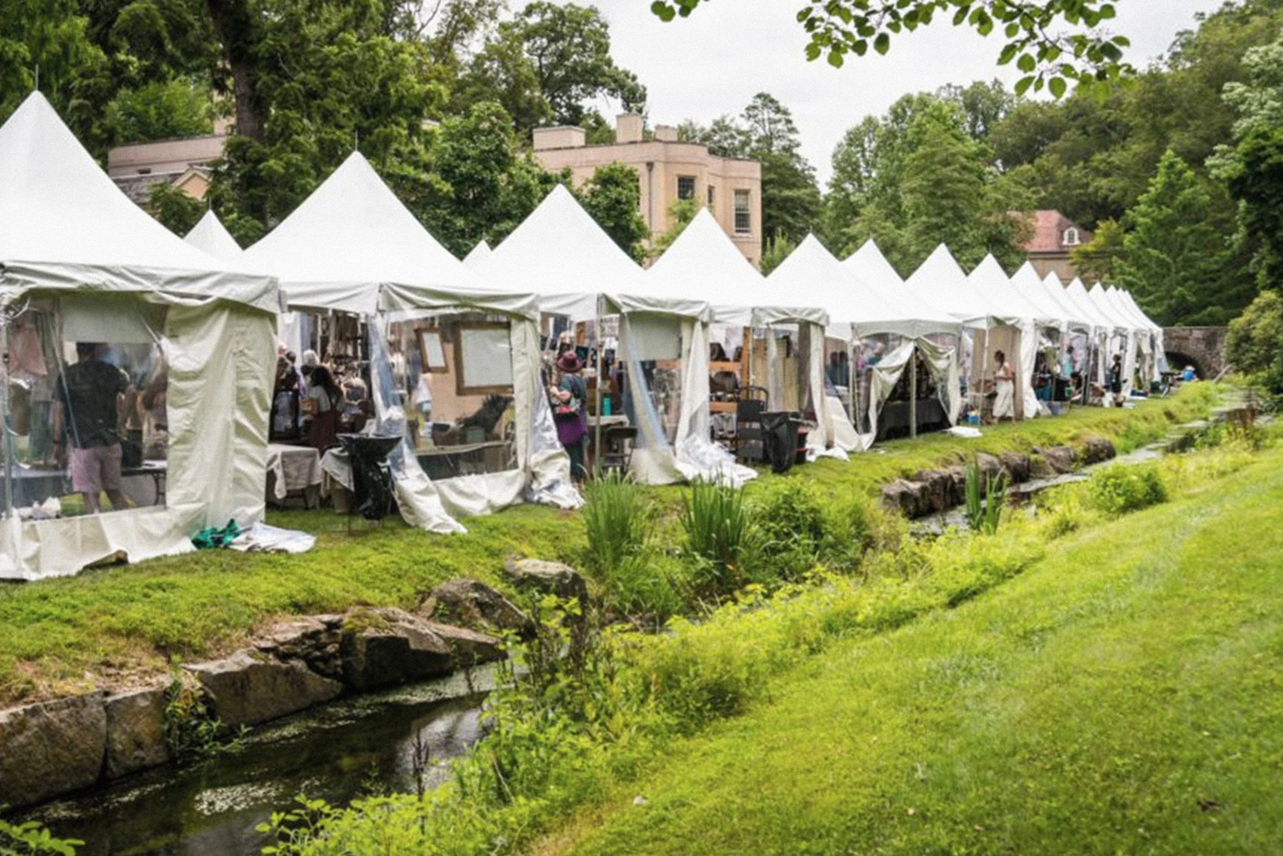 Row of white tents along a creek