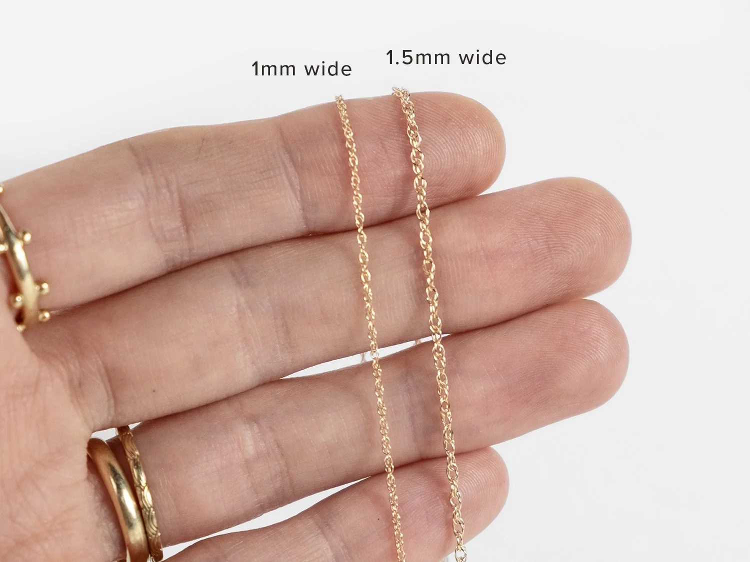 Hand holding gold rope chains in 2 different widths