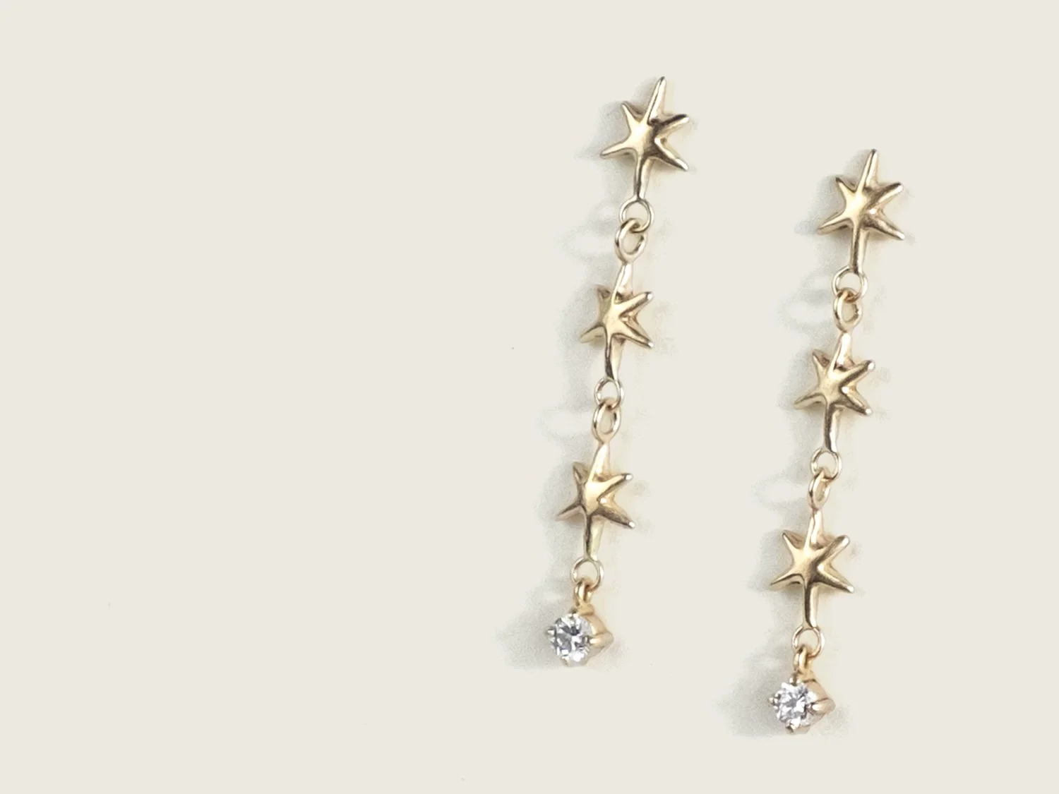 Long gold earrings made of up 3 linked stars and a hanging single diamond