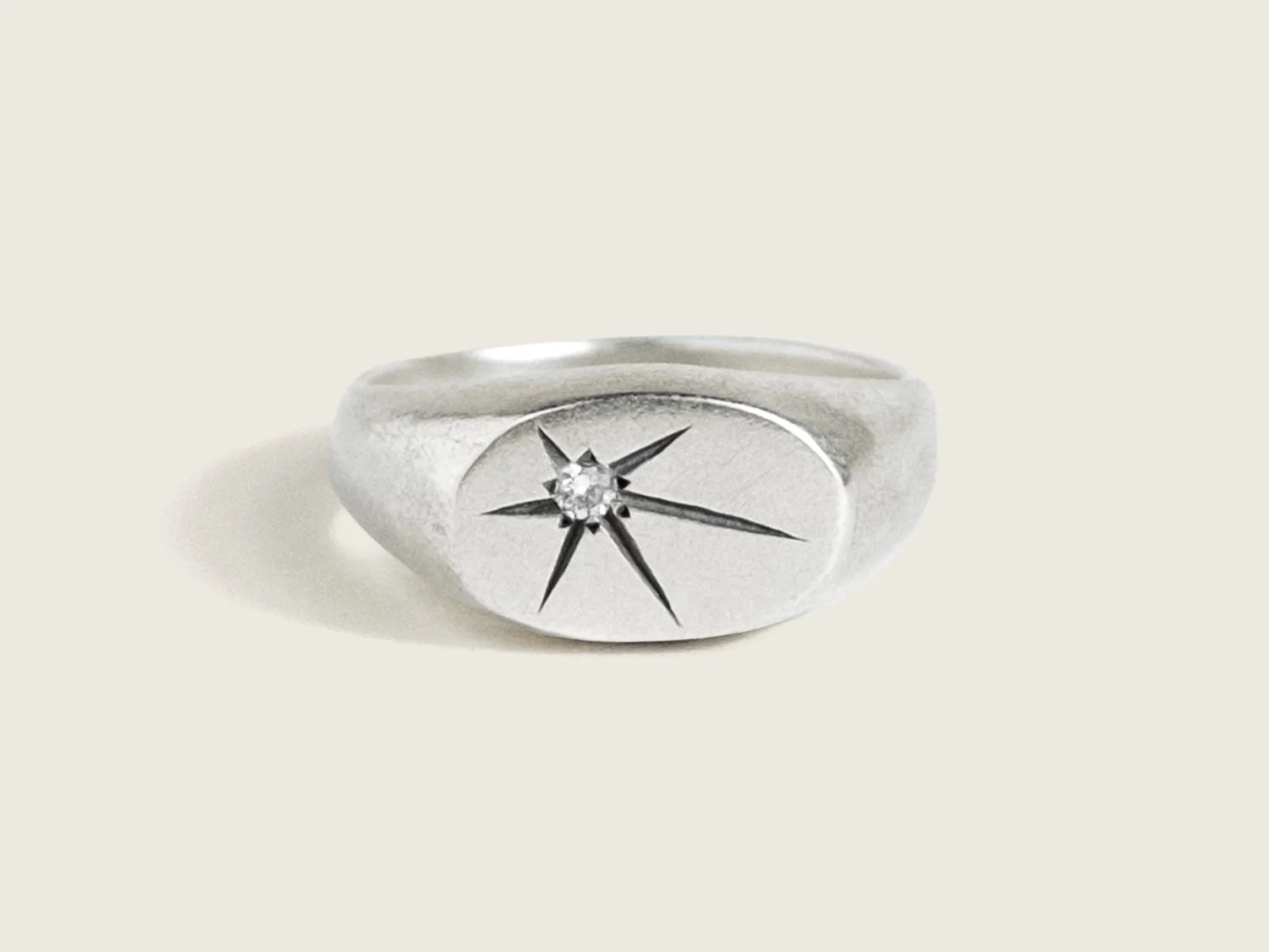 Wide silver signet ring with a single star-set diamond on the flat face
