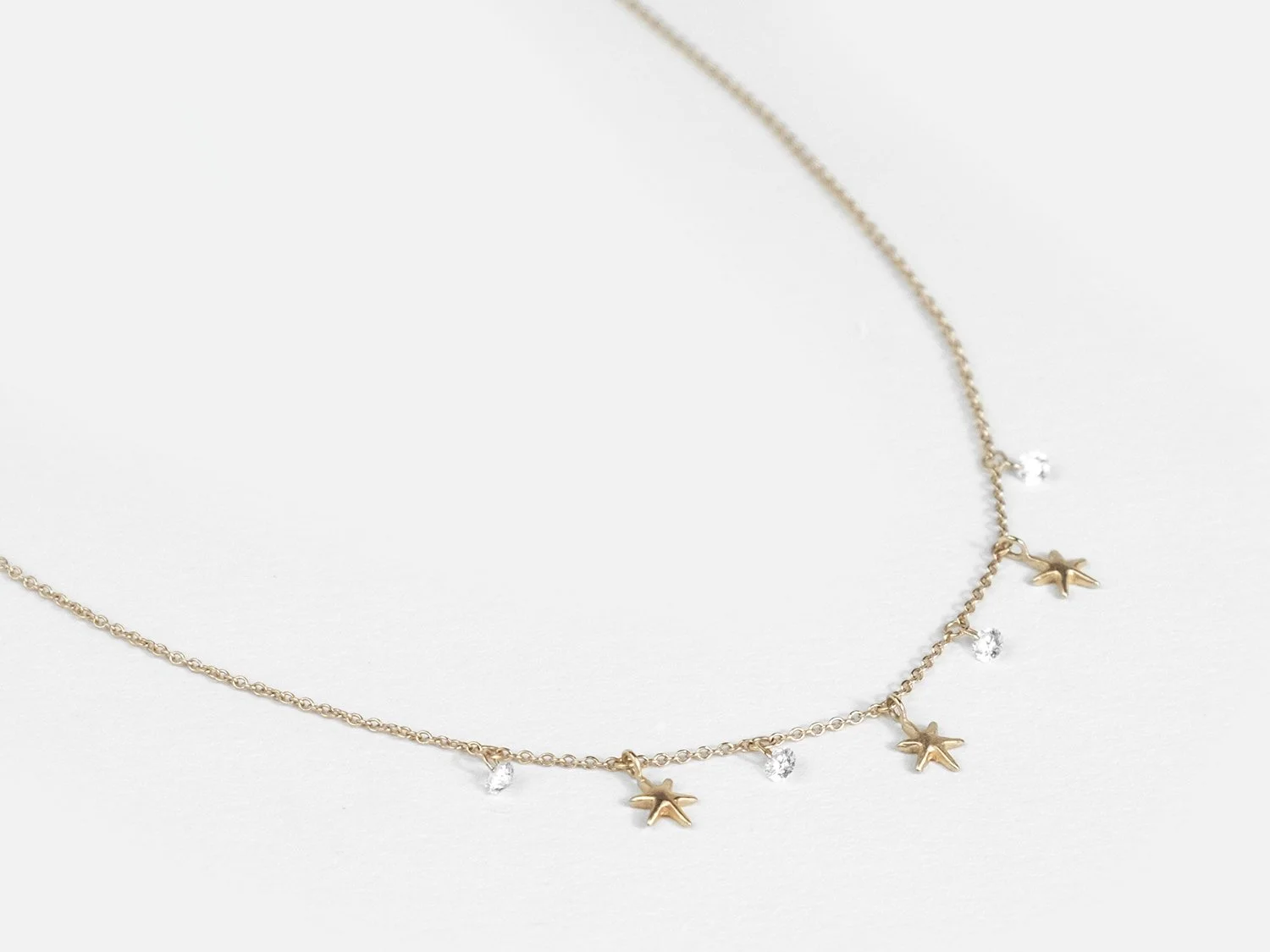 Gold necklace with hanging gold stars and white diamonds