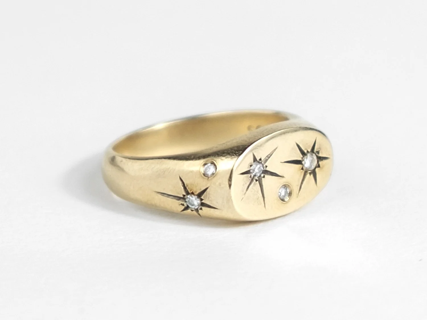 Side view of a wide gold signet ring with star-set diamonds all over the top