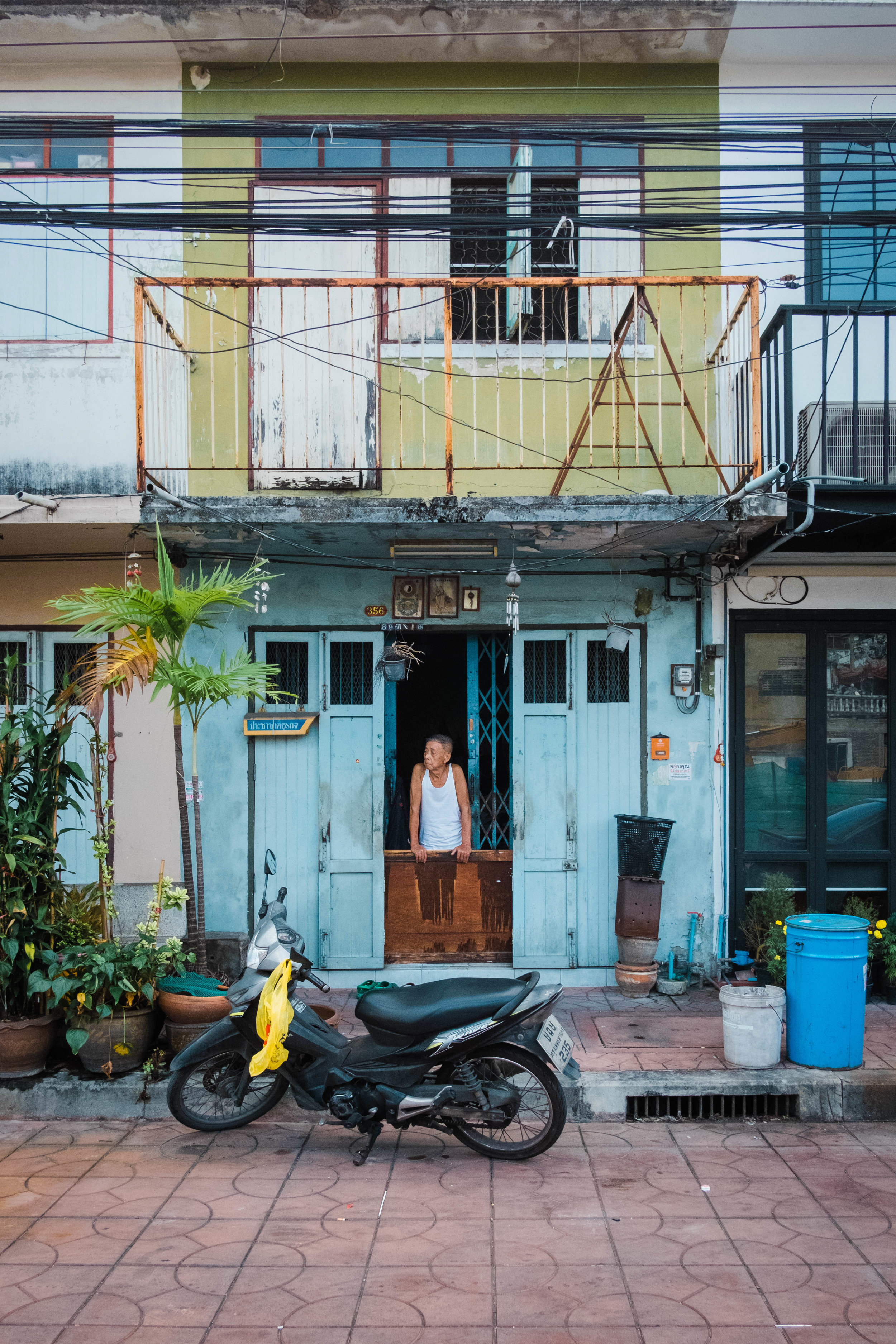 Man looking out of his house in Chinatown, Bangkok, Thailand.