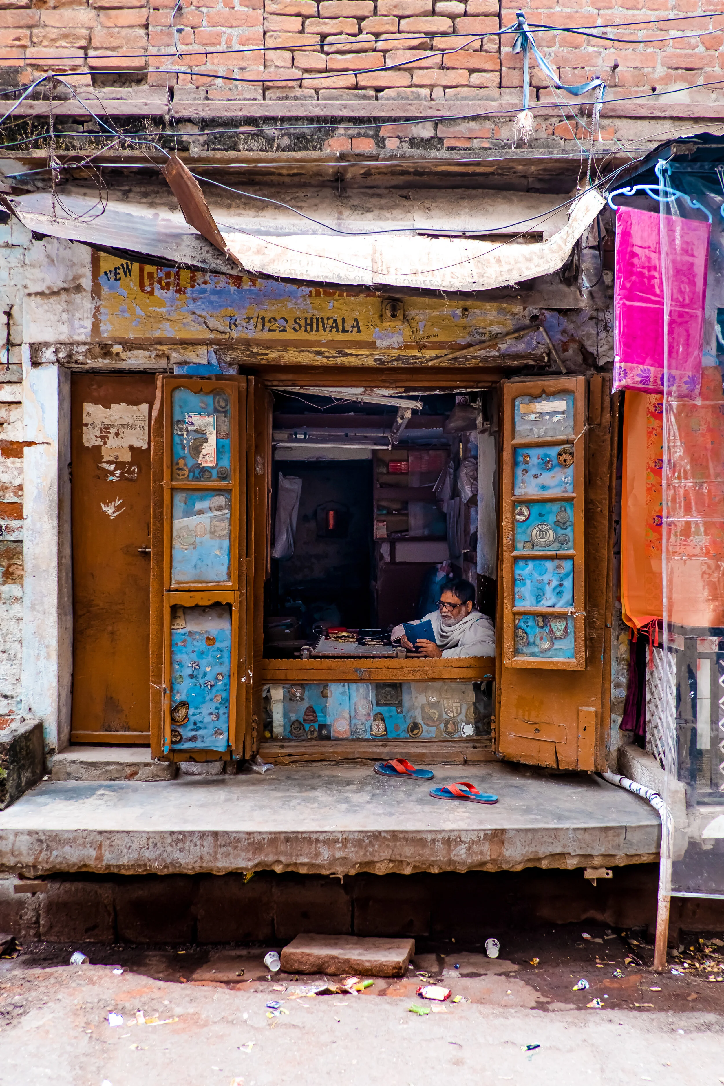 Man on his phone waiting for customers in his shop. Varanasi, India.