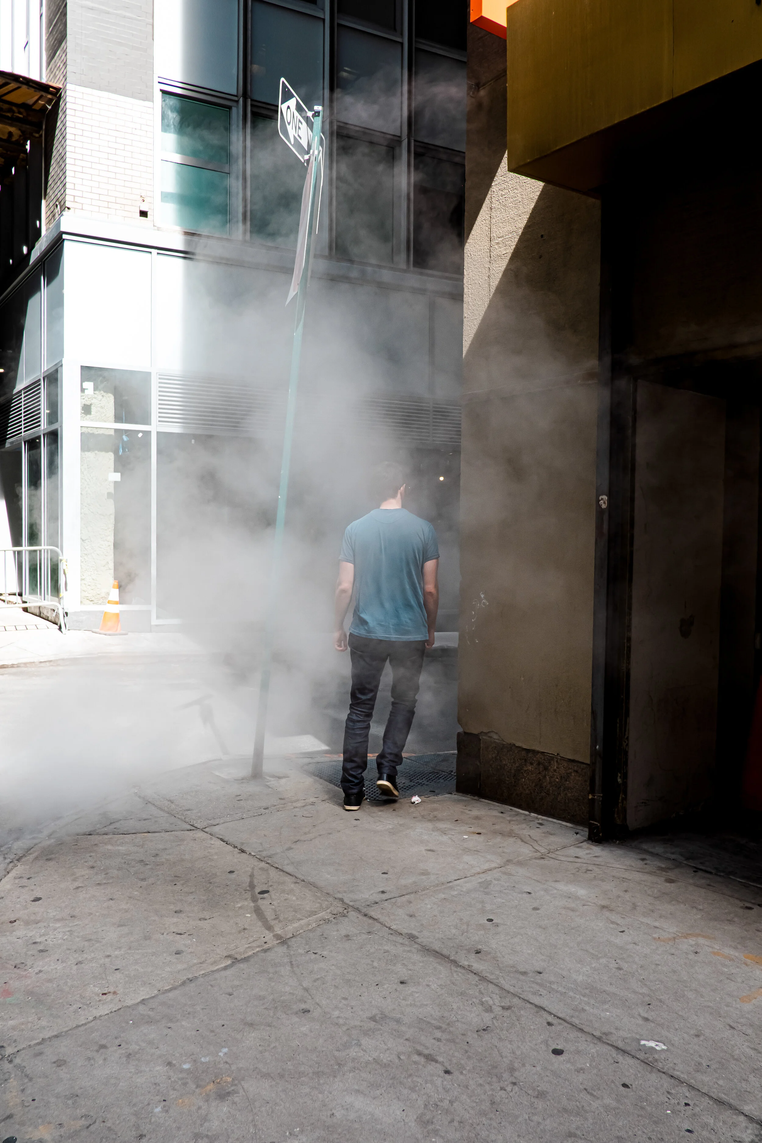 Man walks around the corner through steam in the Financial District in New York, USA.