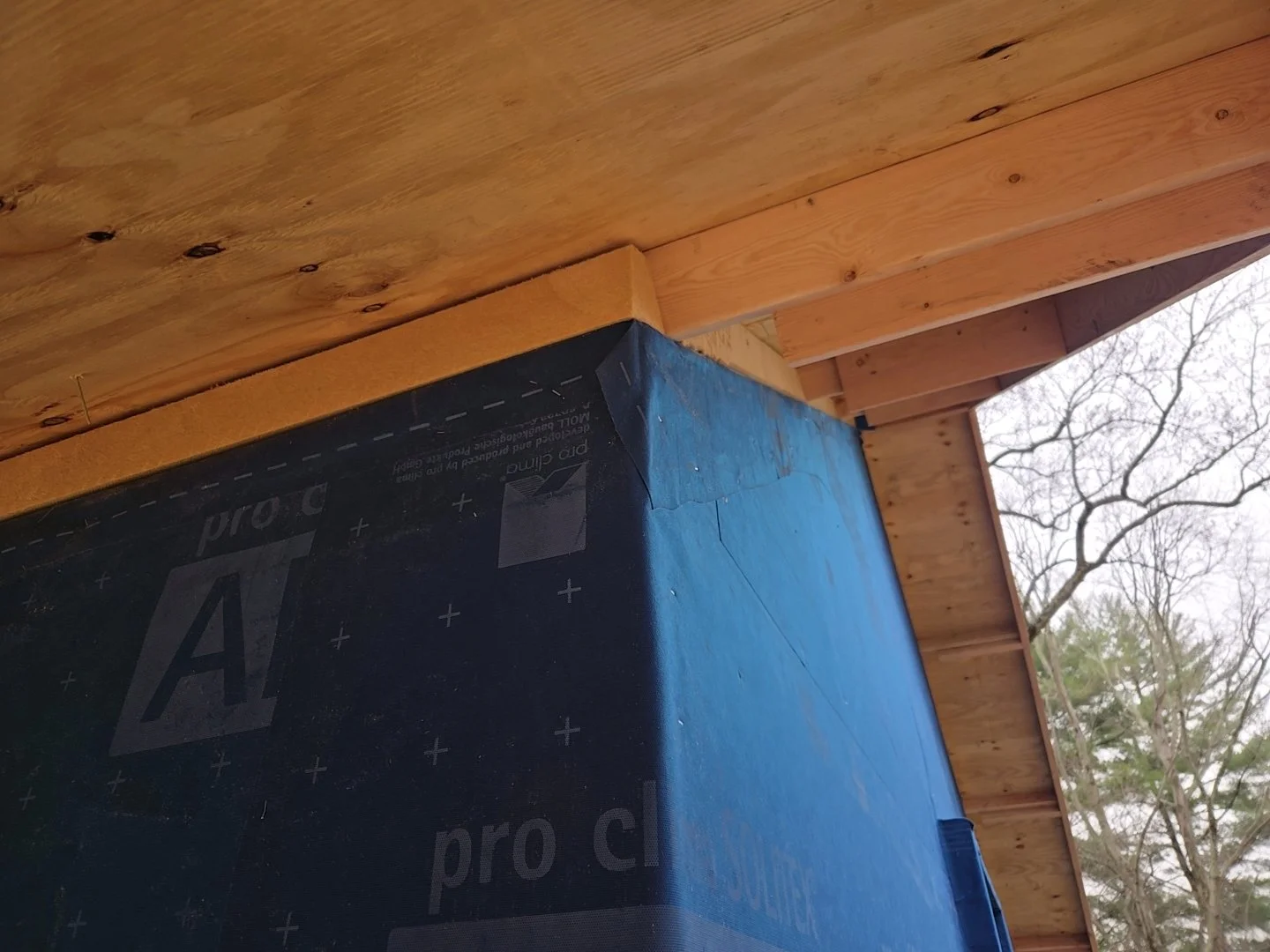 Close-up of roof insulation meeting wall assembly with weather-resistive barrier during construction.