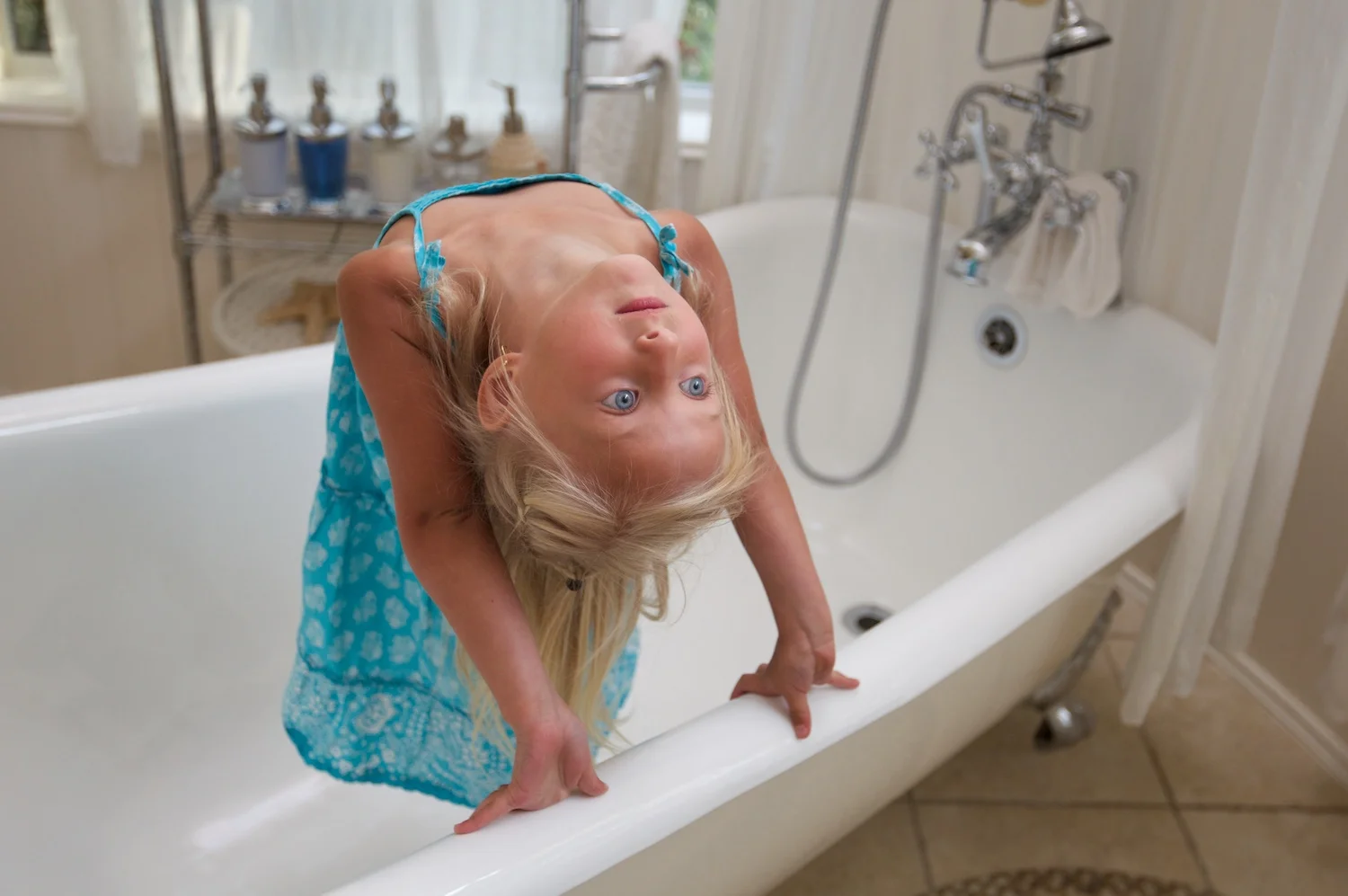 Portrait of a girl in a claw foot tub doing a backbend