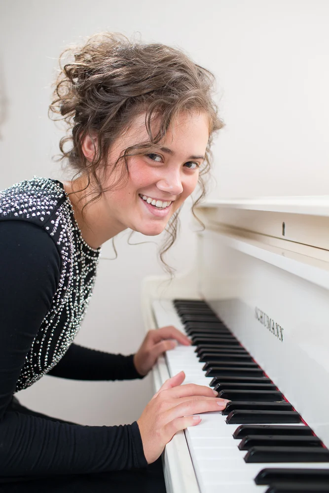 Anna's senior portrait at a white piano