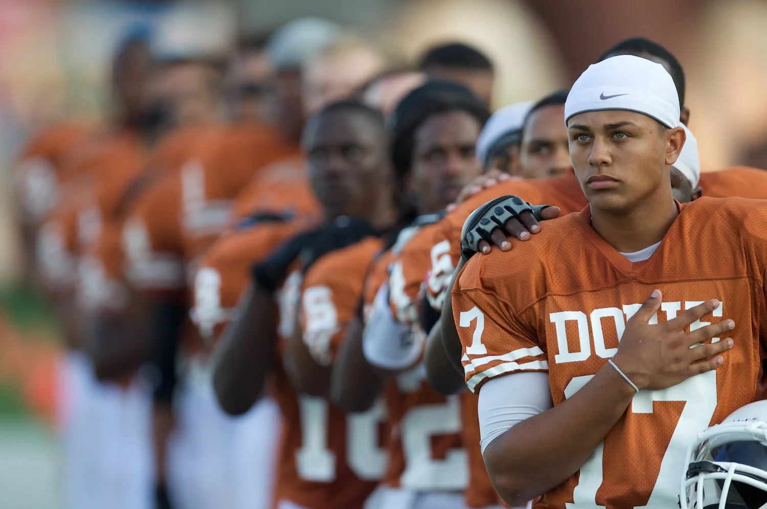 Dobie high school football players standing in line saluting the flag.