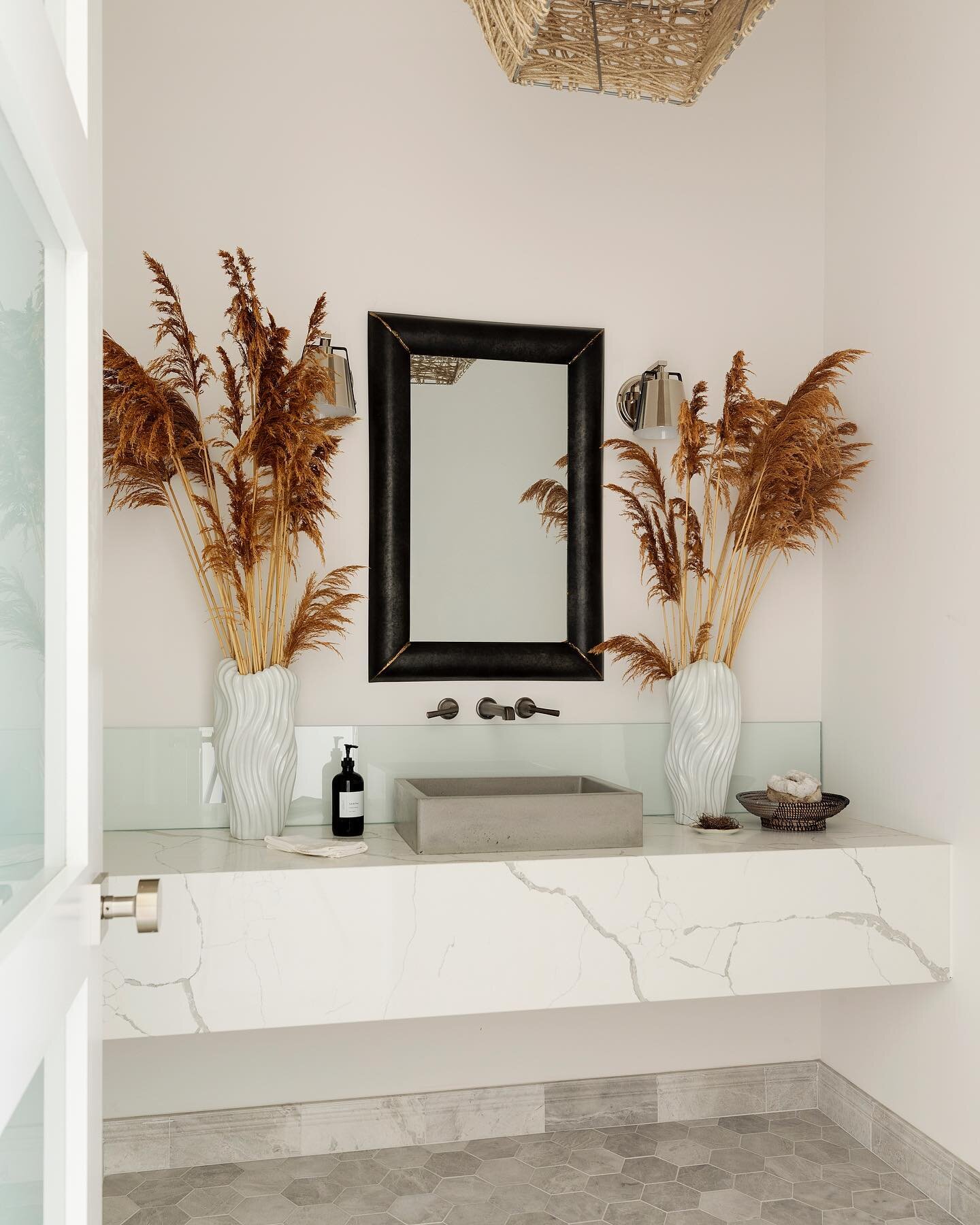 This tropical, breathtaking powder room features designer EMTEK hardware, Calacatta Venice quartz, Hinkley lighting, and dried grasses that make this space feel like you&rsquo;re on vacation from the moment you enter! 

Design ➕ build by @kellifontan