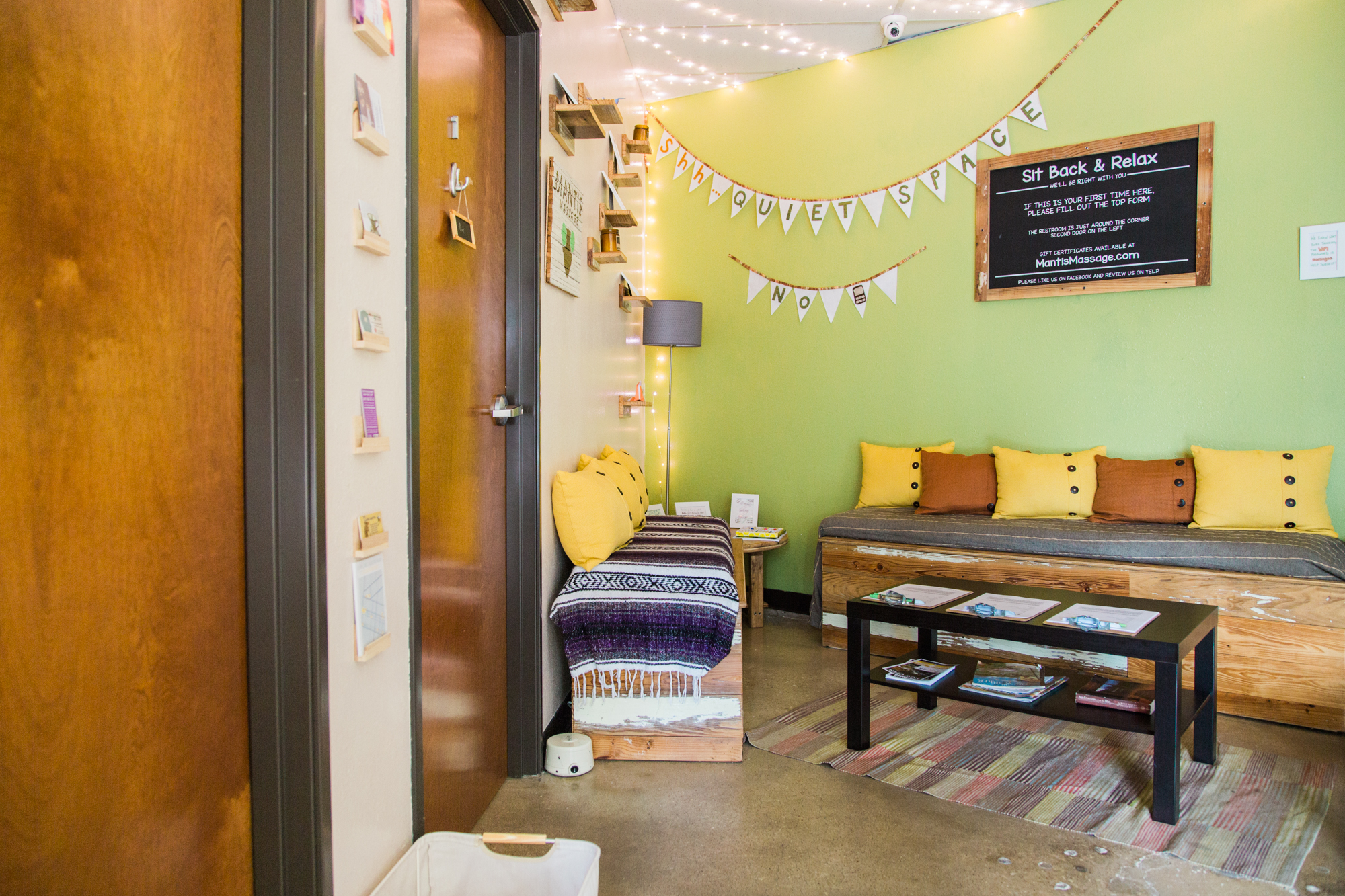  Image shows Mantis Massage Therapy Studio's cozy waiting area in Austin, Texas, plush seating surrounded by warm hues and soft lighting, creating a welcoming sanctuary for relaxation. Take a moment to escape the hustle and bustle of everyday life as