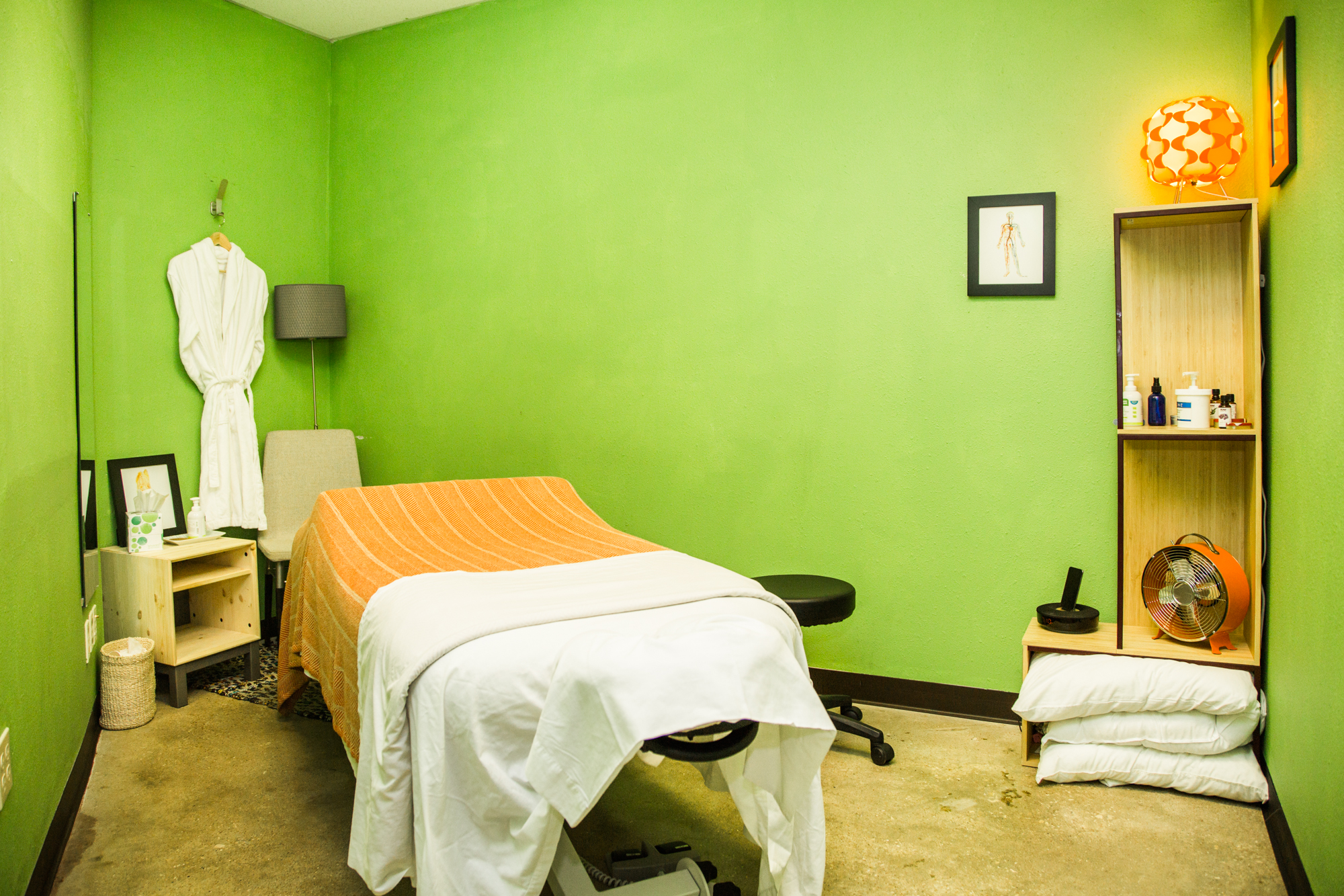  Photograph of a serene private massage room at Mantis Massage in Austin, Texas. Immerse yourself in a calming oasis where soothing green hues create a peaceful ambiance. Our skilled therapists await to provide you with a personalized massage experie