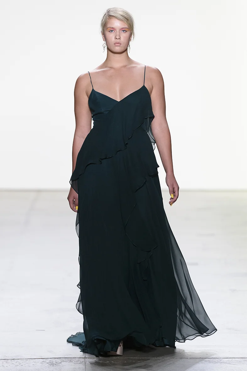 Deep green silk charmeuse and silk chiffon gown with soft V neckline and asymmetrical silk chiffon ruffle detail. A line skirt with natural waist.