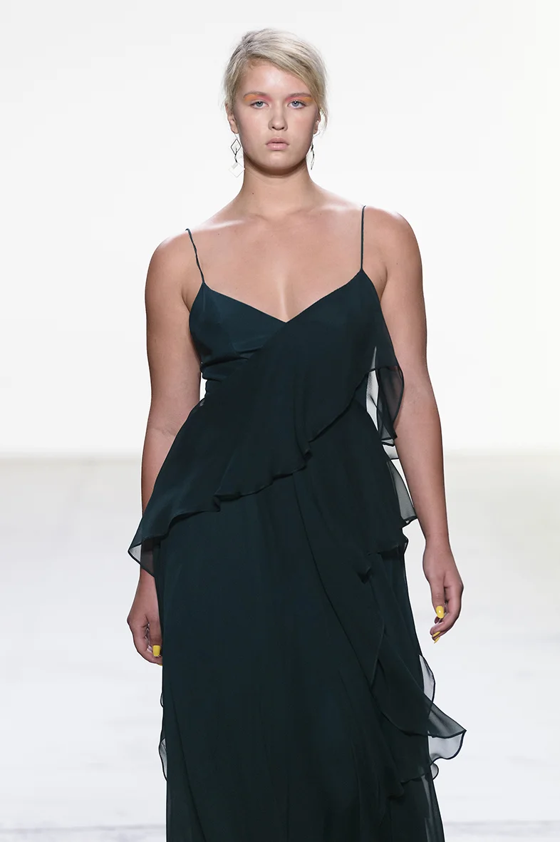 Deep green silk charmeuse and silk chiffon gown with soft V neckline and asymmetrical silk chiffon ruffle detail. A line skirt with natural waist.