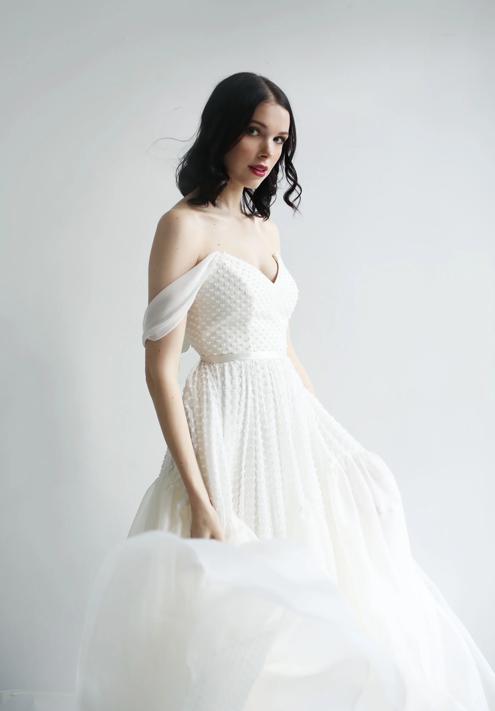 Light ivory silk/cotton bow-dotted chiffon gown. V neck bodice with versatile chiffon straps, waist belt, and very full chiffon dot and silk organza paneled skirt train. Zipper up the back.