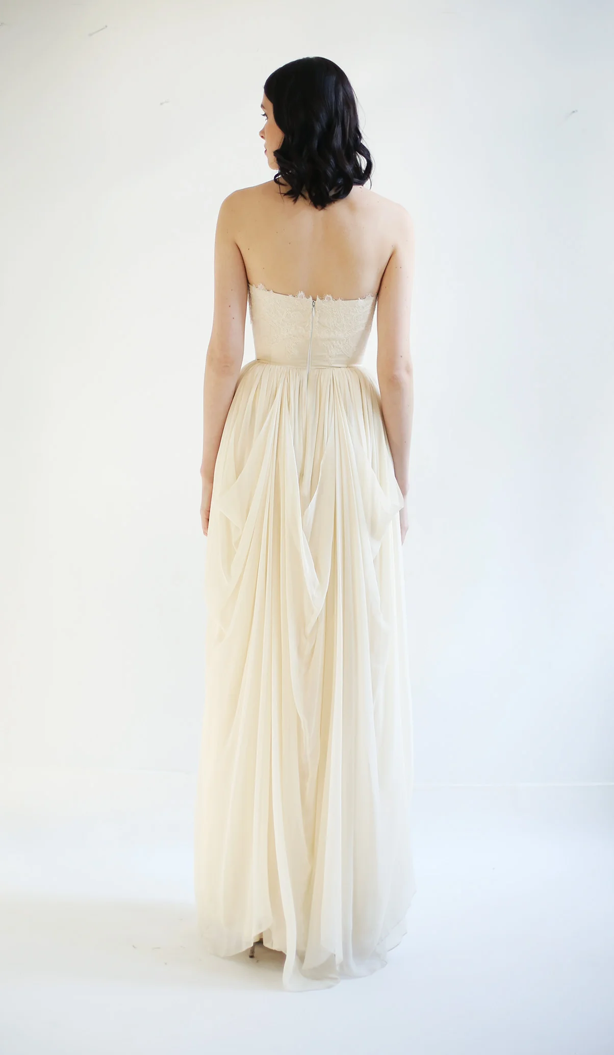 fully-boned sweetheart bodice is a beautiful silk duchess satin. It features hand-sewn and draped bust detail with lace embellishments. The skirt is made of a delicate ivory silk chiffon
