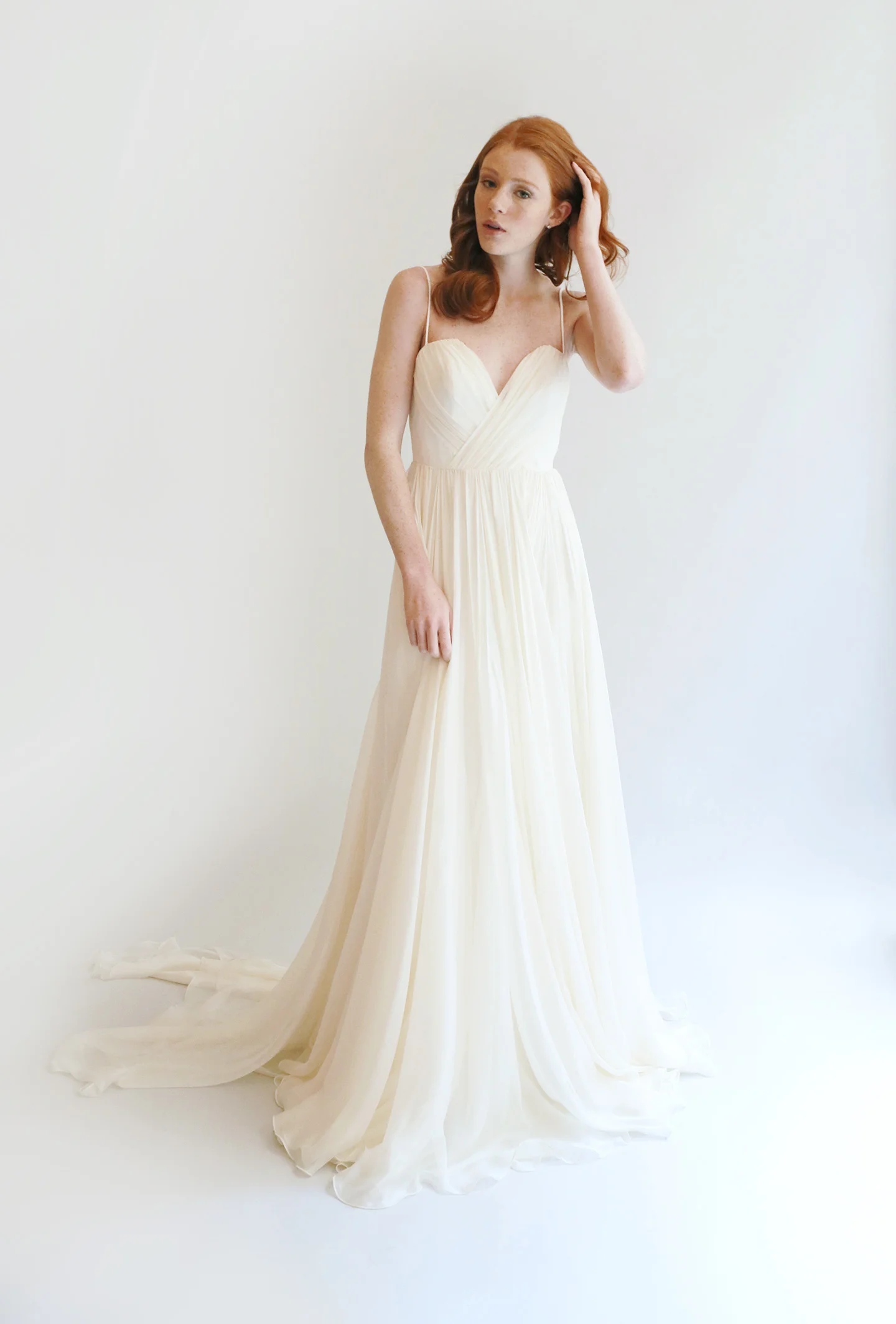 Long flowing gown in ivory with ultra-fine silk chif- fon skirt. Sweetheart boned bodice with spaghetti straps features a deeper dip in the front with a V plunge in the back