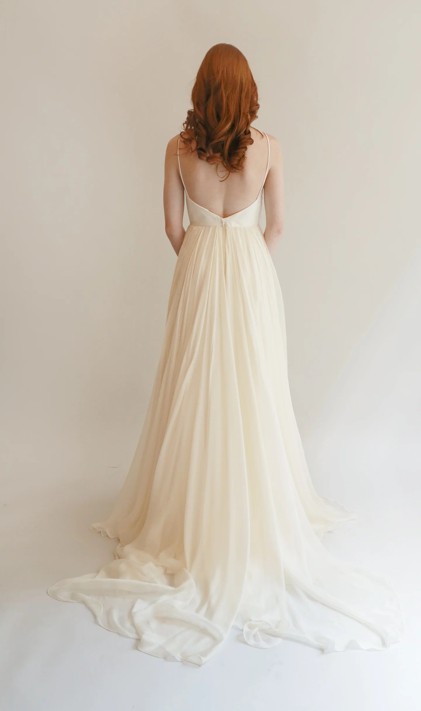 Long flowing gown in ivory with ultra-fine silk chif- fon skirt. Sweetheart boned bodice with spaghetti straps features a deeper dip in the front with a V plunge in the back