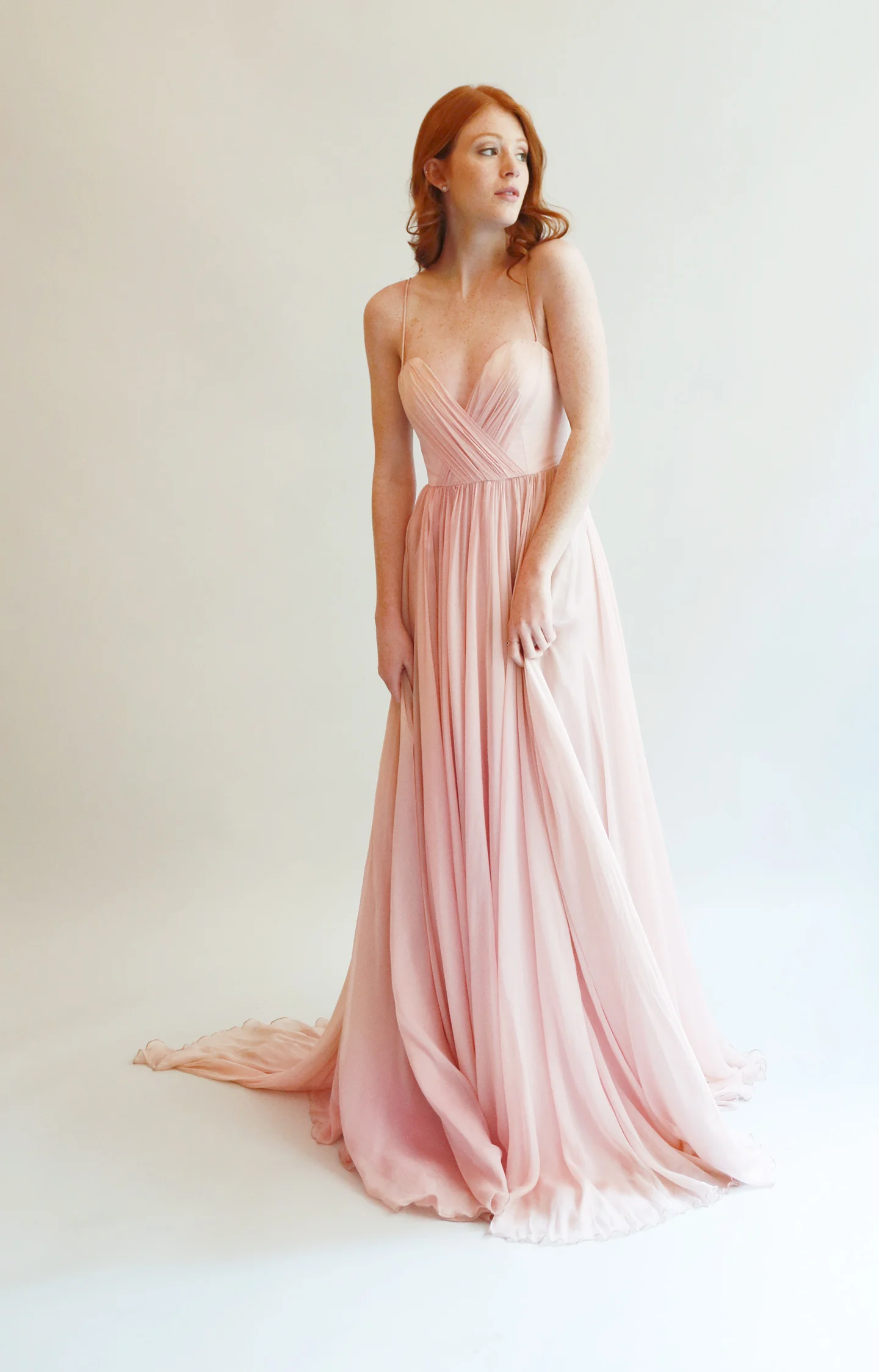 Long flowing gown in ivory with ultra-fine silk chif- fon skirt. Sweetheart boned bodice with spaghetti straps features a deeper dip in the front with a V plunge in the back