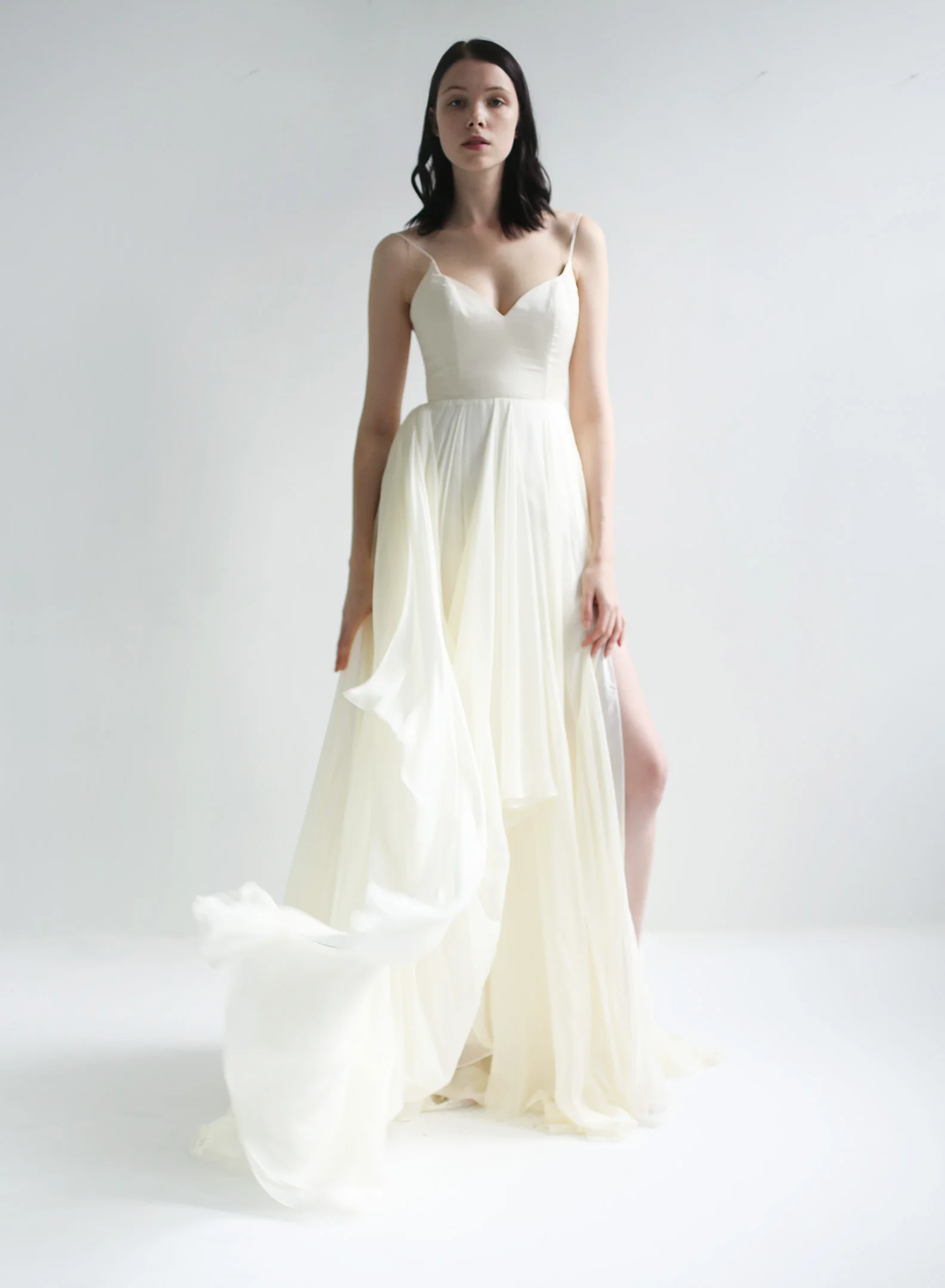  Fully boned curved -V bodice with spaghetti straps and V-plunge in the back. Skirt is made of assymmetrically draped high quality, feather-light silk chiffon in ivory