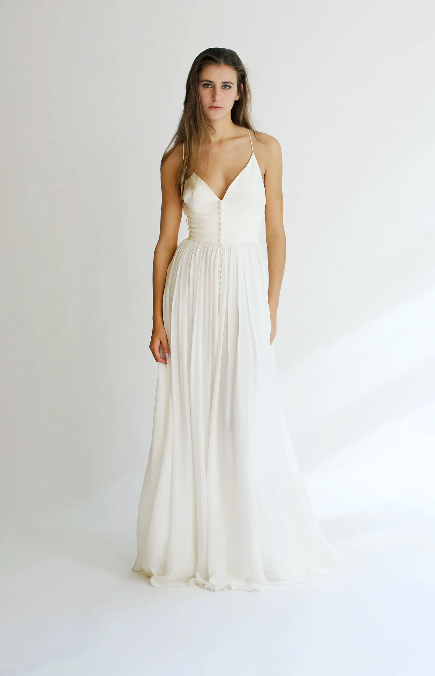 Copy of Light ivory V-neck gown with racer-back in silk chiffon with non-funtioning button detil down the front. Bodice is shaped with darts. The skirt is A-line with side pockets
