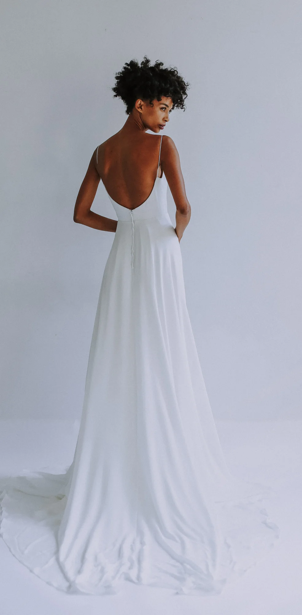 light ivory sweethearted V-neck bodice gown with slim A-line skirt in silk georgette. Fully boned bodice with spa- ghetti straps. Long train. Closes with zipper up the back.