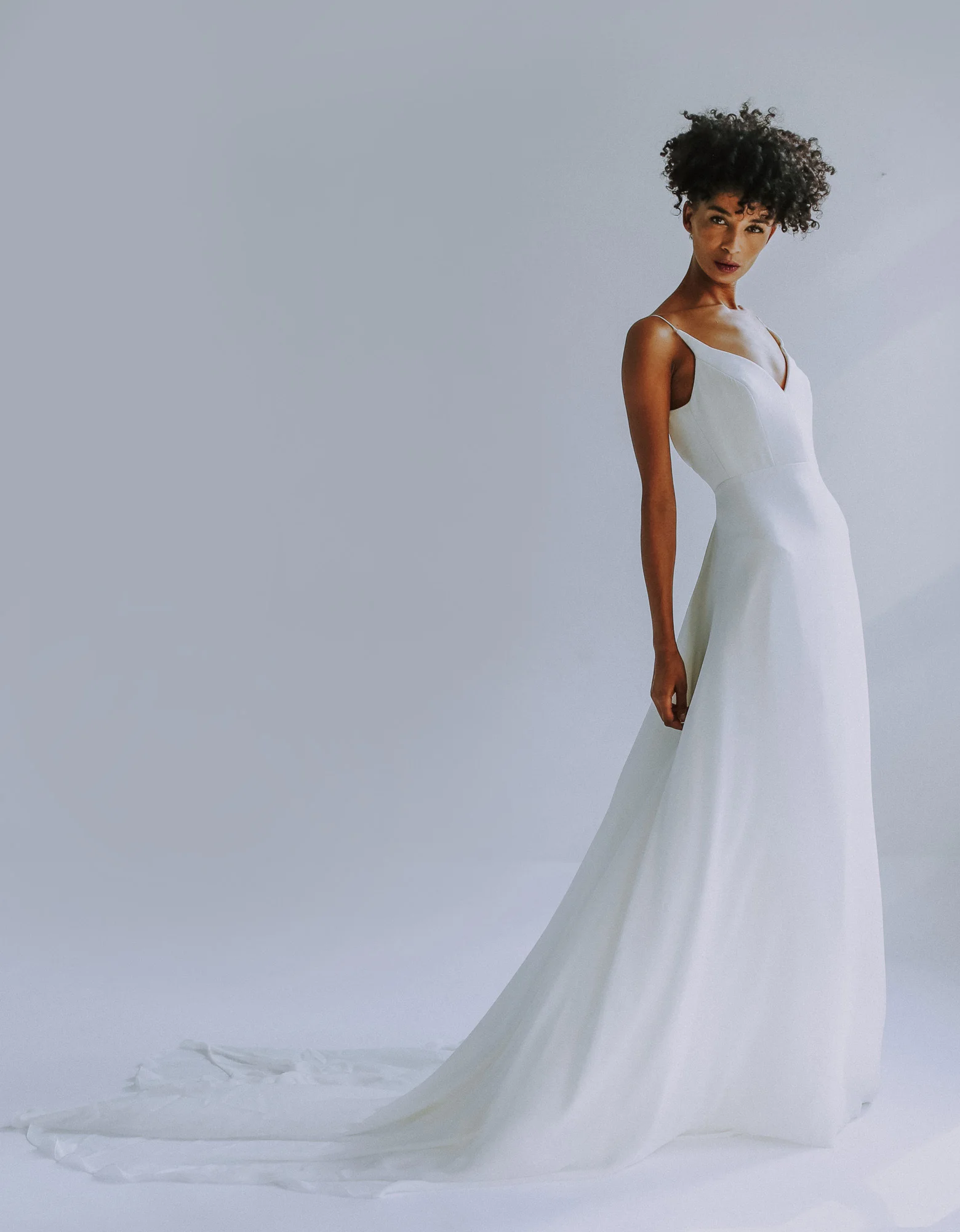light ivory sweethearted V-neck bodice gown with slim A-line skirt in silk georgette. Fully boned bodice with spa- ghetti straps. Long train. Closes with zipper up the back.