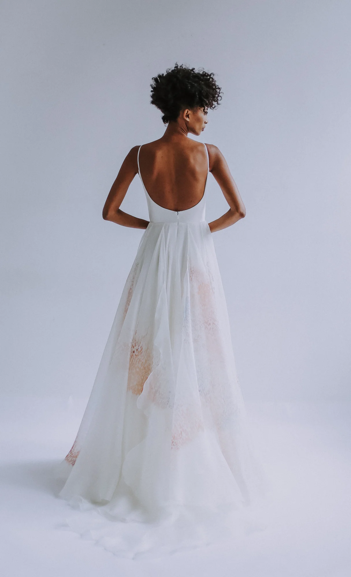 Ivory scoop-neck bodice in silk twill, with spaghetti straps, and low scoop back. Skirt in multi-hued silk organza “Je t’aime” print with cascading wave detail.