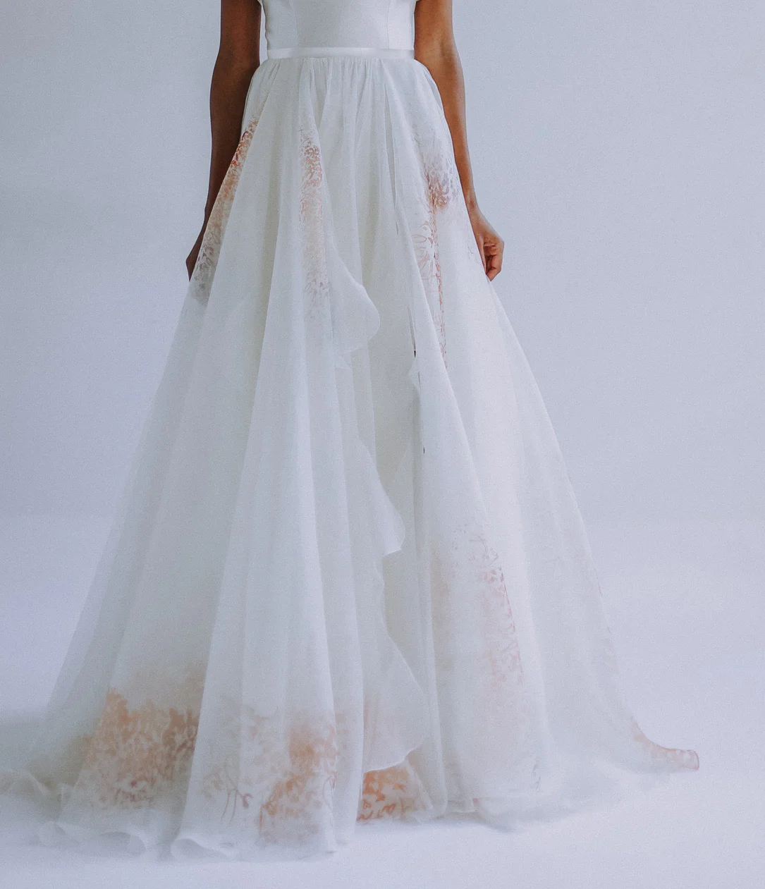 Skirt in multi-hued silk organza “Je t’aime” print iwith cascading wave detail. Slit on side, and long train. and zipper up the back. Available in all ivory.