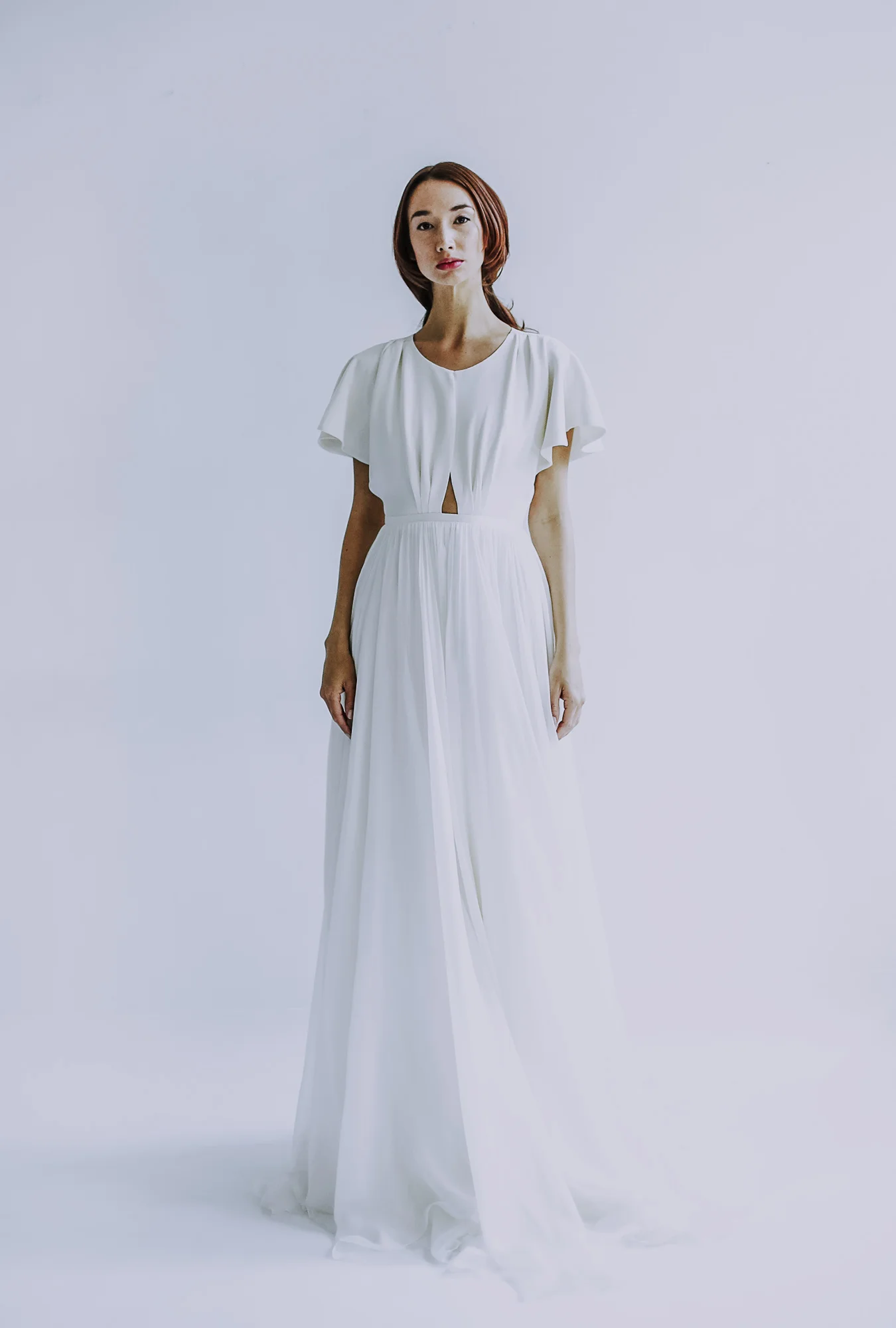 ivory silk crepe flutter sleeve bodice, shaped with darts, open keyholeback, and overlap slit in front with fitted waist band. Closes with zipper up back.
