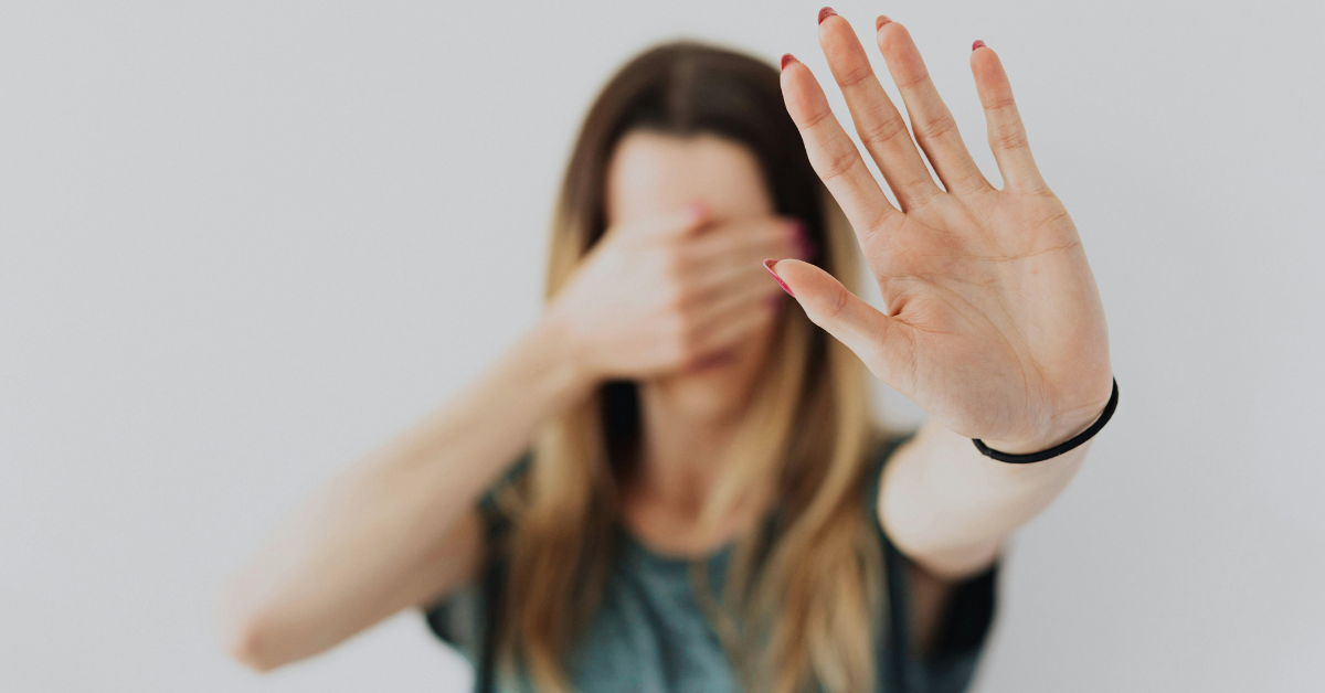 Person covering their eyes with hand raised to block something out, symbolizing ignoring irrelevant ads