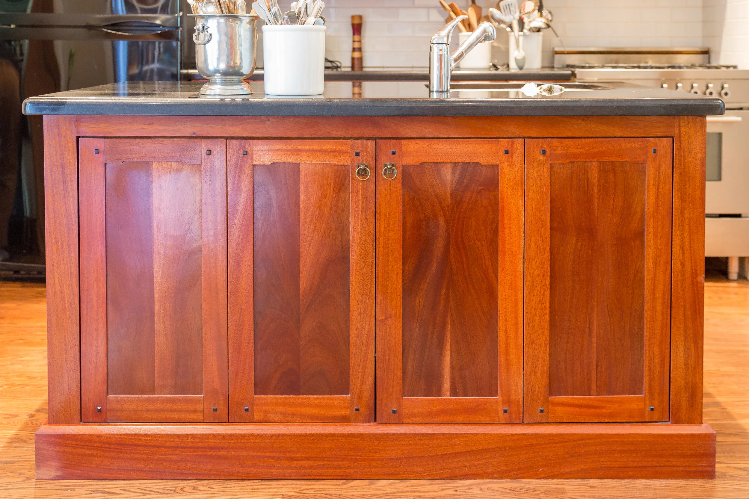 Custom Greene and Green inspired kitchen island. Features solid mahogany construction, ebony accents and a television unit enclosed behind the doors.