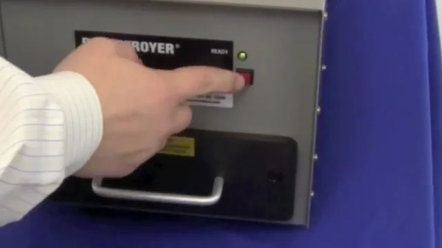 Pressing the degauss button on a drawer style degausser.