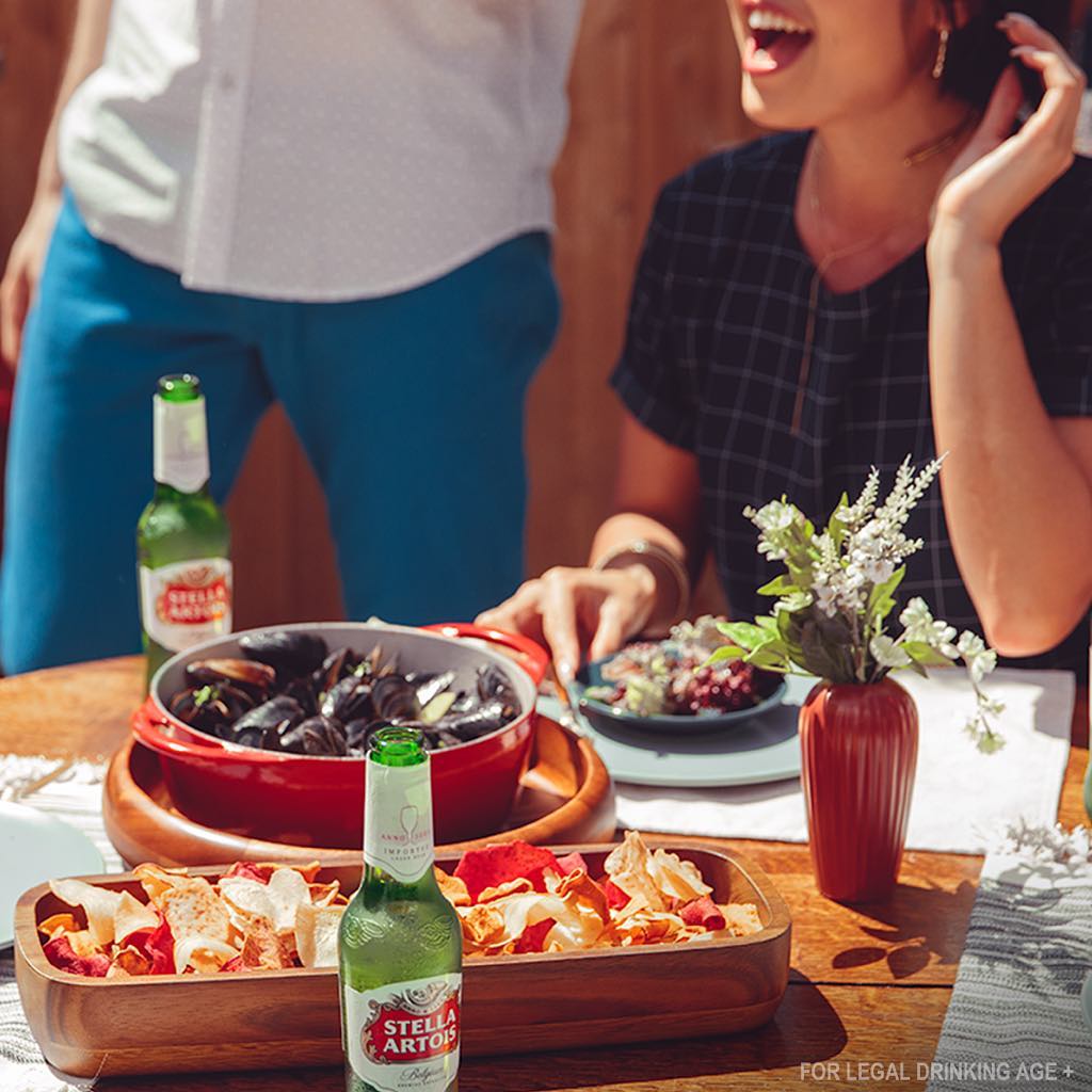 Mussels, Stella Artois. People are gathered outside with bottles of beer.