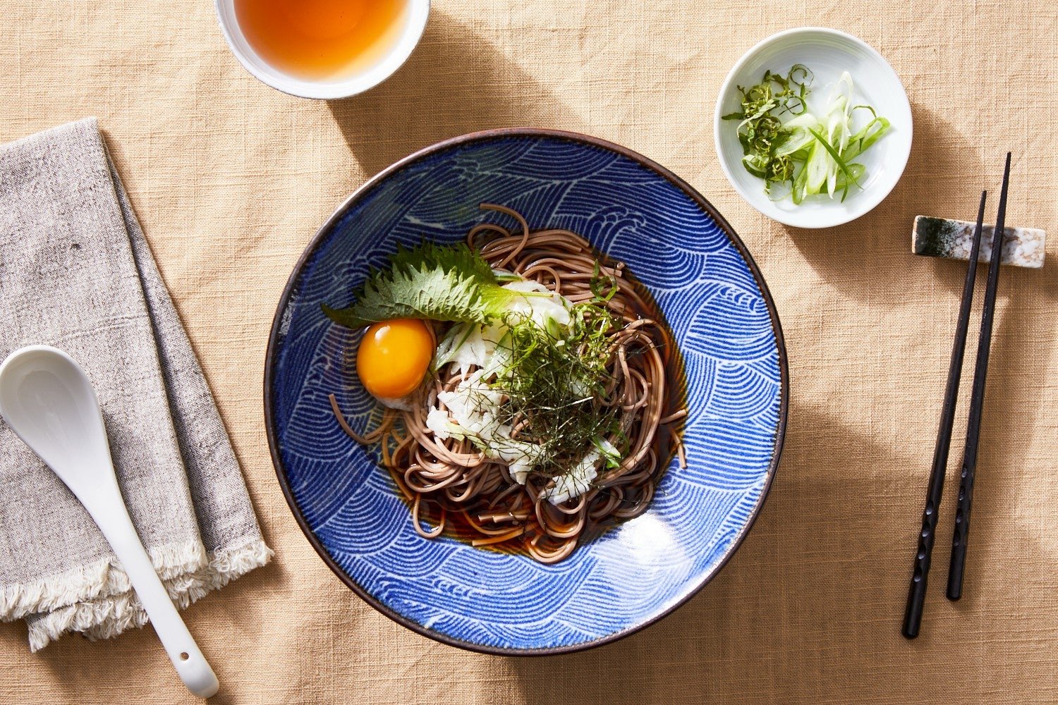 A bowl of soba noodles with an egg yolk.