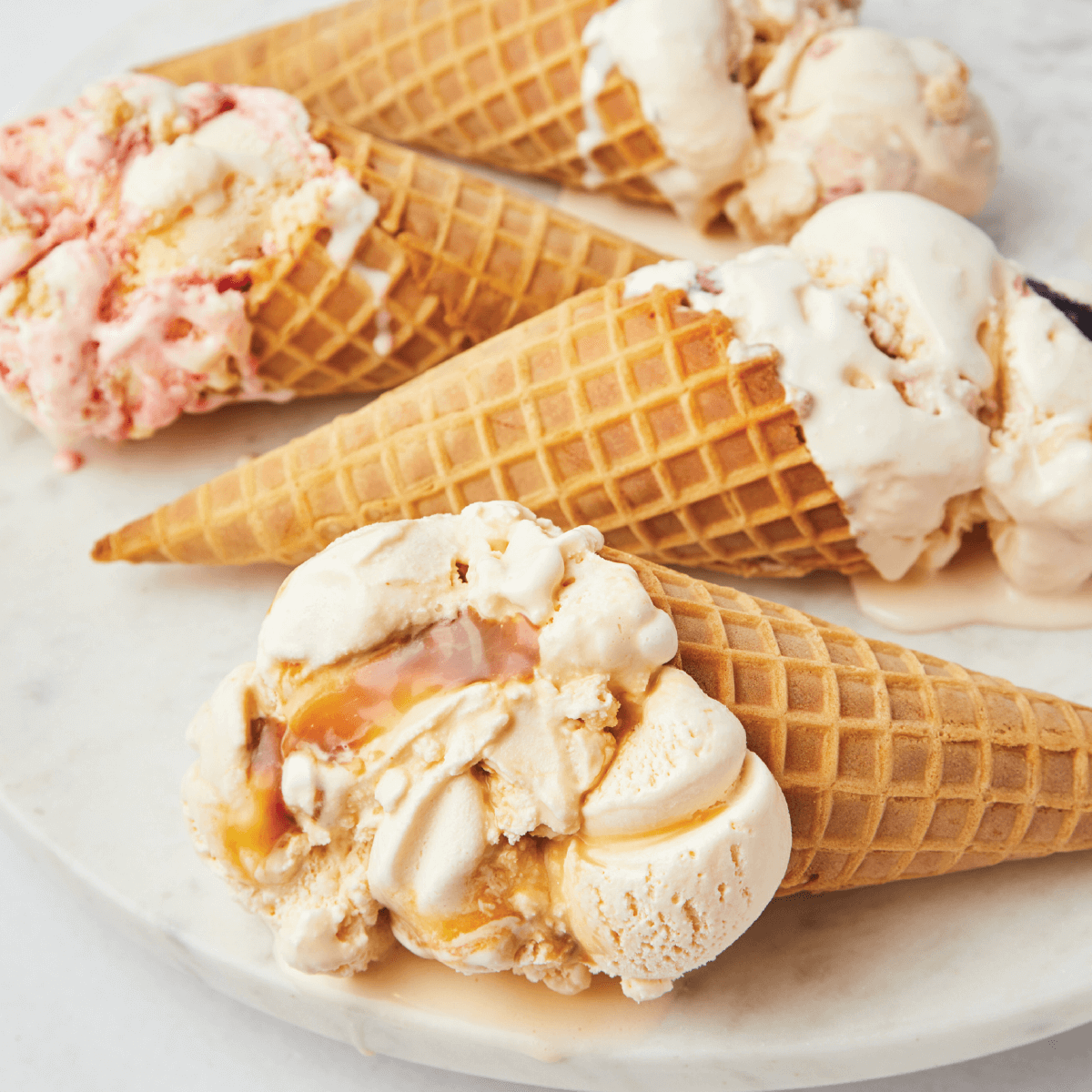 Four waffle cones with ice cream on a plate