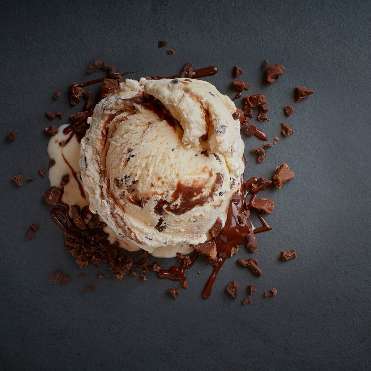 A scoop of ice cream with a swirl of fudge and chunks of chocolate.