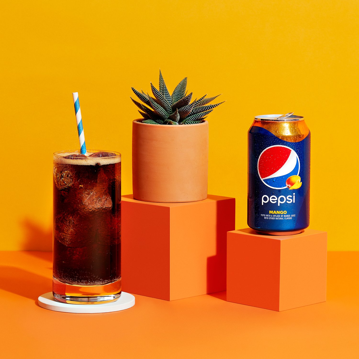 A glass of Pepsi Mango with a can next to it.