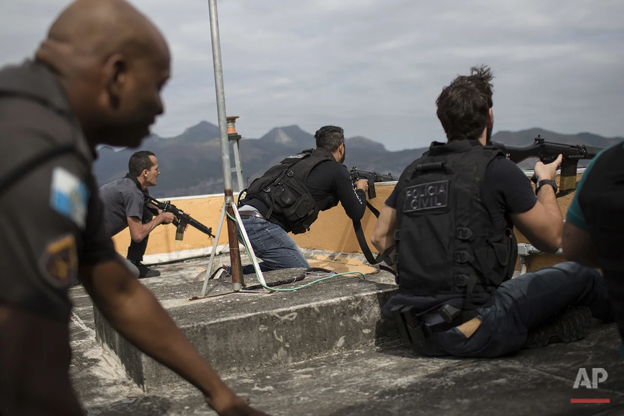 In this July 7, 2016 photo, police exchange gunfire with drug traffickers at the "pacified" Alemao slum complex in Rio de Janeiro, Brazil. Half a dozen officers had entrenched themselves behind a cable car station while they shot it out with suspected drug traffickers in the sprawling cluster of slums in north Rio. Shootouts erupt daily, even in slums where community policing programs had successfully rewritten the narrative in recent years. (AP Photo/Felipe Dana)