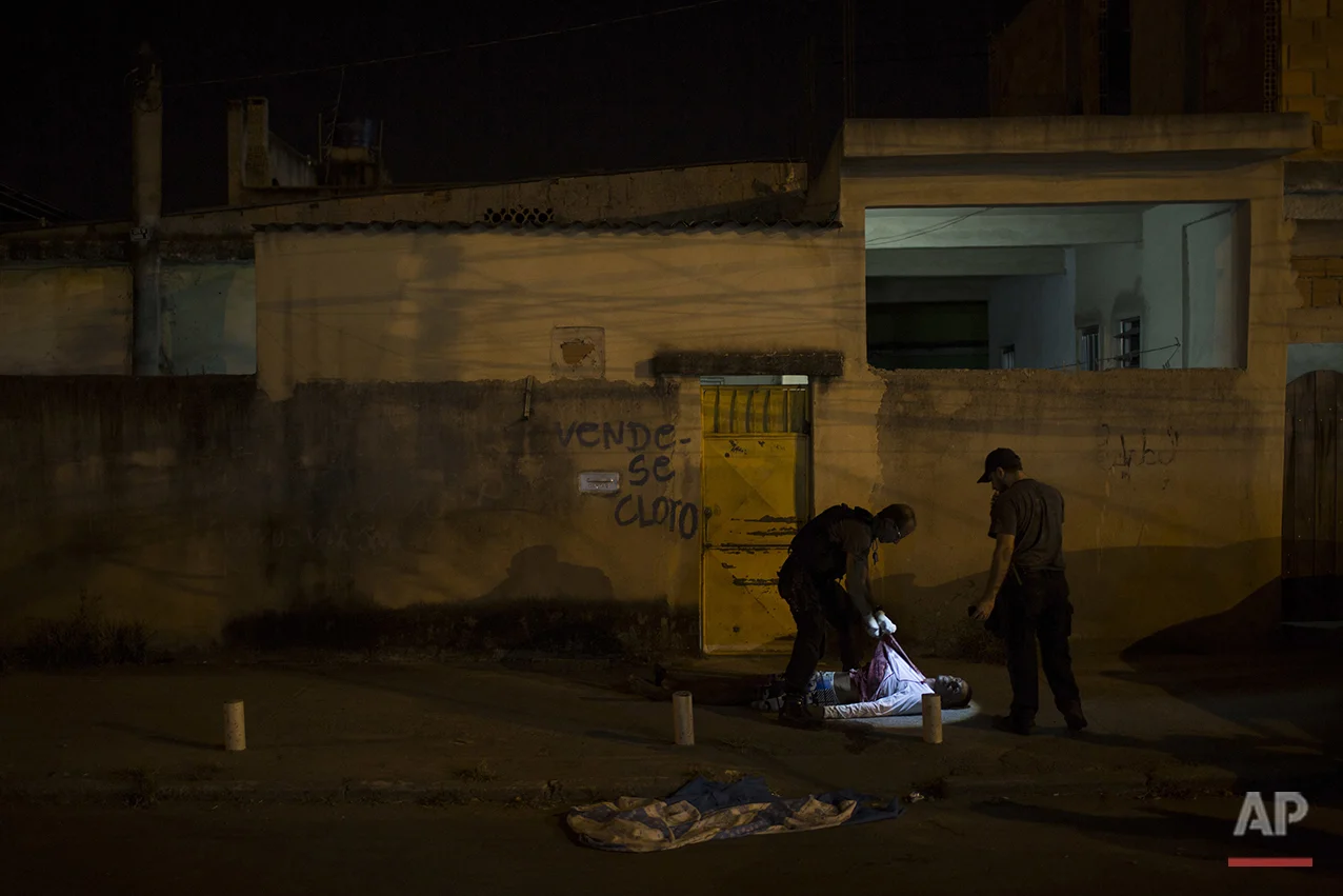 In this July 16, 2016 photo, police responding to a call find the body of a young black man in the middle of a residential street in Caxias, greater Rio de Janeiro, Brazil. Rio's ambitious security push to bring crime down and seize control of certain slums ahead of the 2016 Summer Games is crumbling. Overall slayings are on the rise in 2016, the victims overwhelmingly young, black men. (AP Photo/Felipe Dana)