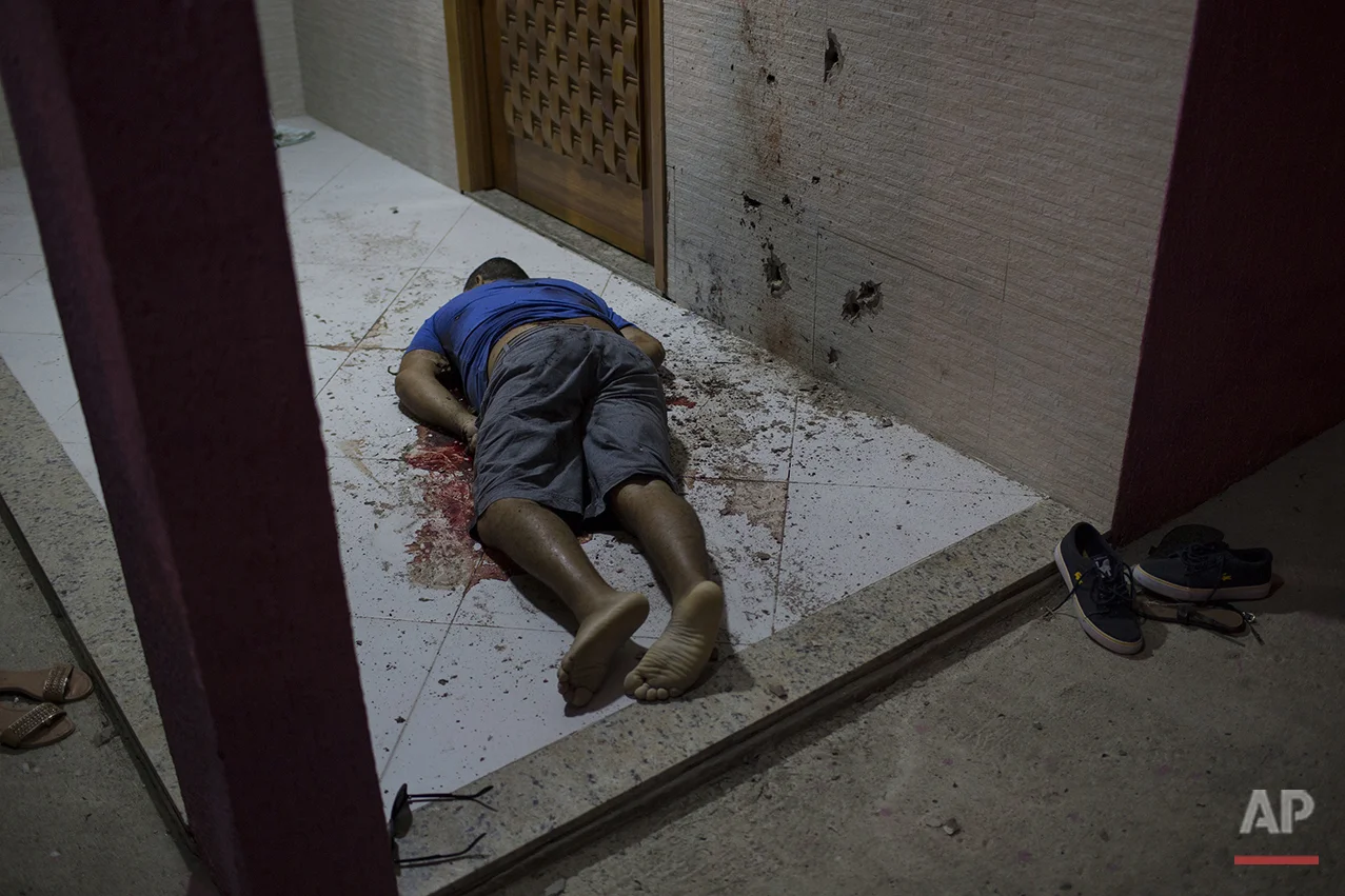 This July 13, 2016 photo shows the body of a man who was taken from the inside of his home and shot dead at the entrance of his home in Nova Iguacu, greater Rio de Janeiro, Brazil. Scenes of impunity and violence play out daily in many of Rio's hundreds of slums, known here as favelas, and other outlying areas. Police believe this homicide was gang-related. (AP Photo/Felipe Dana)