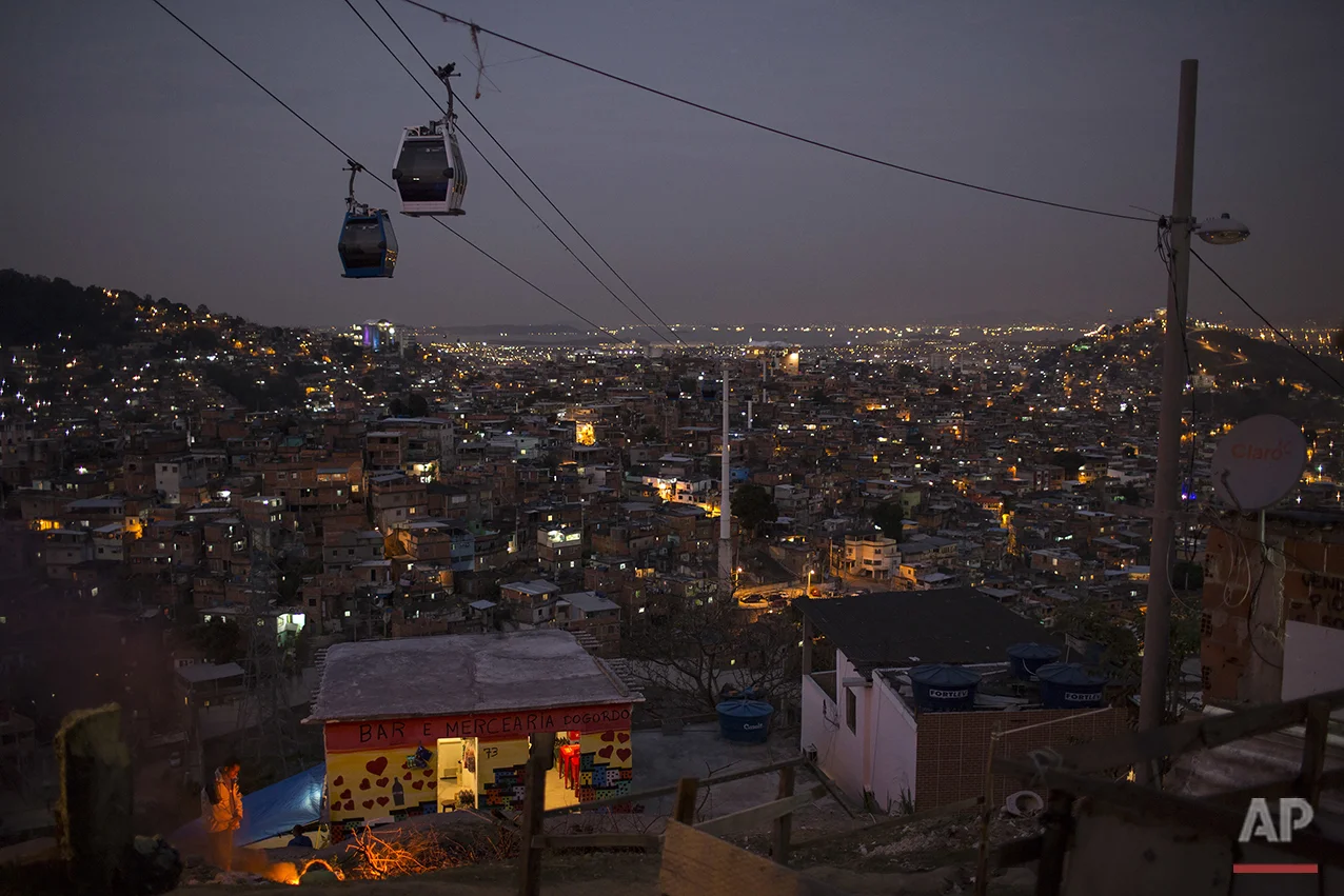 In this July 19, 2016 photo, cable cars transport commuters over the Complexo do Alemao, a sprawling cluster of slums in north Rio de Janeiro, Brazil. Just a short drive from upscale Rio districts like Ipanema and Copacabana, steep and narrow entryways lead to slums where poverty and gun violence dominate daily life for hundreds of thousands of residents.(AP Photo/Felipe Dana)