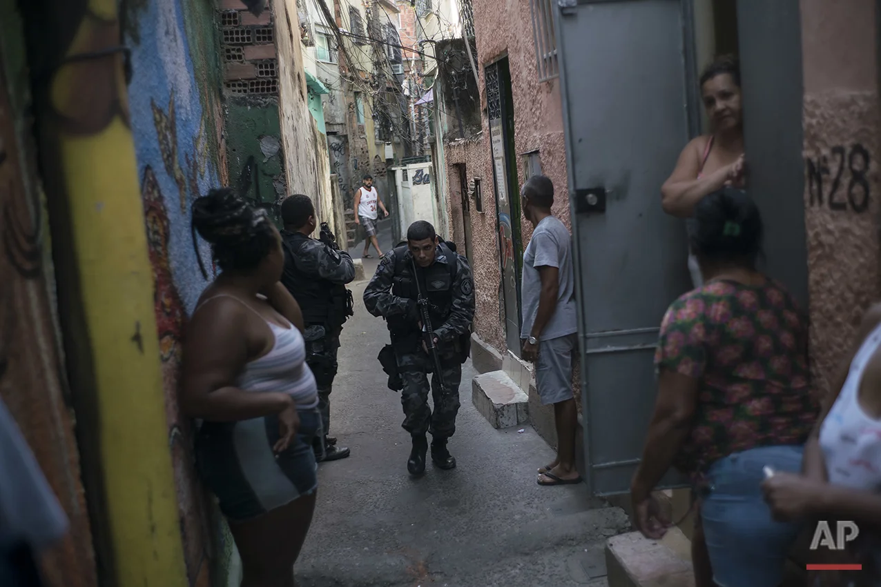 In this June 29, 2016 photo, a police officer patrols among residents during an operation against drug traffickers at the "pacified" Jacarezinho slum in Rio de Janeiro, Brazil. The Pacification Police Units, known by the Portuguese acronym UPP, were created in 2008, setting up community stations in at-risk areas, mostly near sports venues, posh tourist districts and downtown. A drug gang leader called the program a "facade." He said that drug dealers were initially worried and kept a low profile, but soon it was back to business as usual. (AP Photo/Felipe Dana)