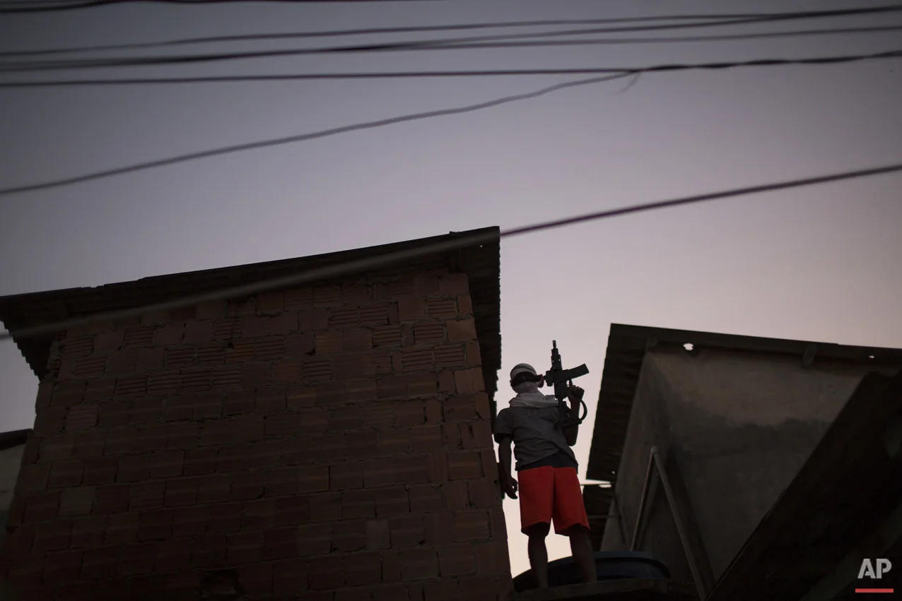 In this July 11, 2016 photo, a young drug trafficker poses for a photo holding his weapon at a slum in Rio de Janeiro, Brazil. (AP Photo/Felipe Dana)