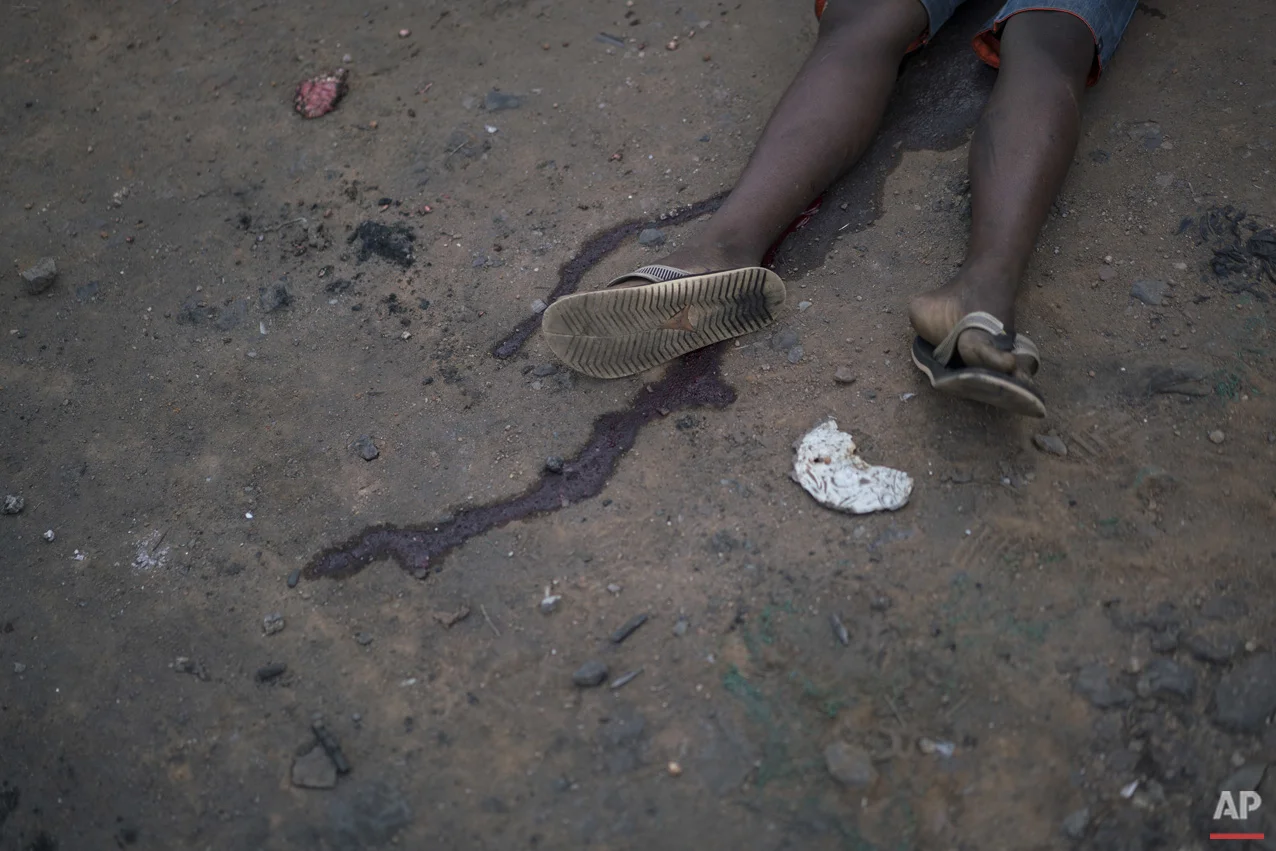 This June 30, 2016 photo shows the body of a teenage boy who was killed while walking outside of his home turf in a gang controlled area of Rio de Janeiro, Brazil. Later in the day, according to residents, the father went to denounce his son's death