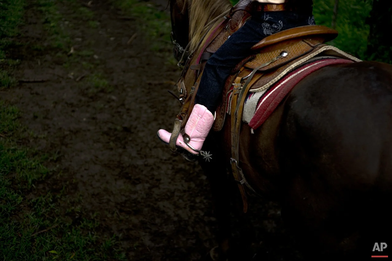 In this July 29, 2016 photo, cowgirl Dariadna Corujo rides her horse near a farm in Sancti Spiritus, central Cuba. At the tender age of 6, Dariadna is already an expert barrel racer and calf roper, wearing pink boots as she competes in rodeos on the flat grasslands of central Sancti Spiritus province. (AP Photo/Ramon Espinosa)