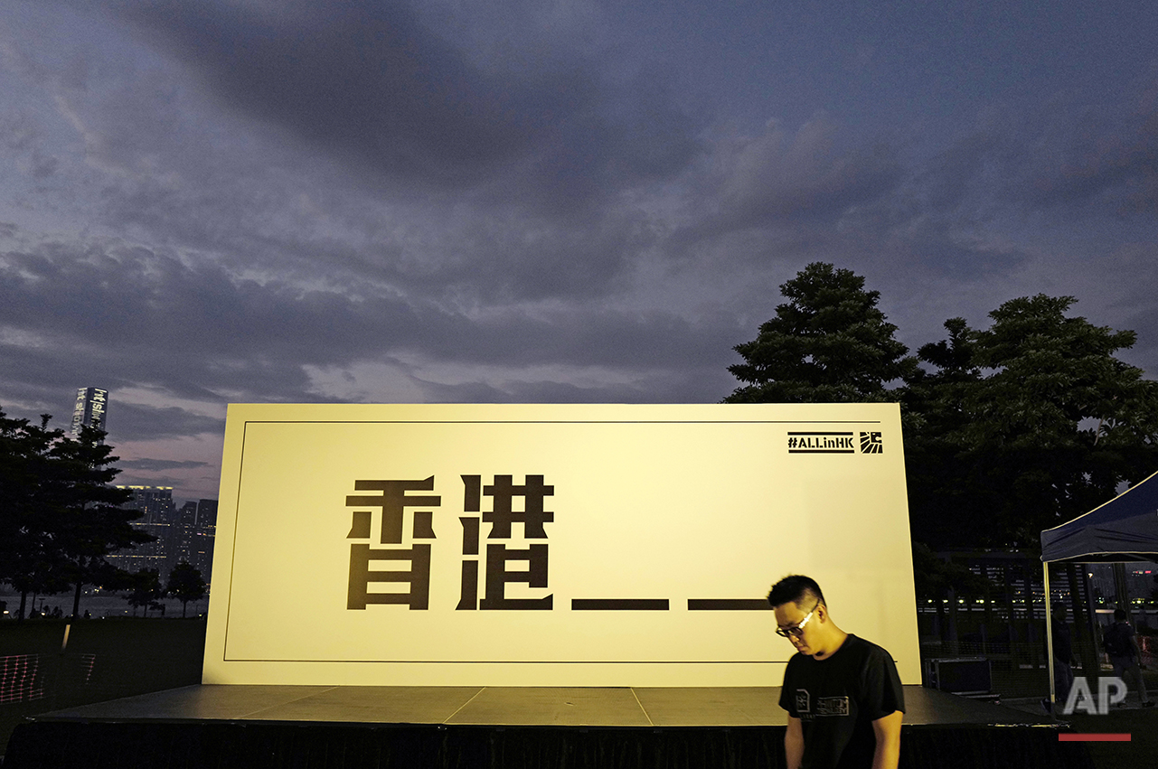  In this Aug. 28, 2016, photo, a supporter walks past a backdrop for a pre-election rally in Hong Kong. Characters reads "Hong Kong" leaving out the word "independence," a reference to the government's attempt to disqualify candidates promoting indep